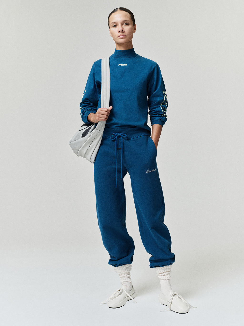 Womens Low Rise Sweatpant in blue with drawstring waist tapered legs and elastic cuffs styled on a model with sneakers as Bottoms
