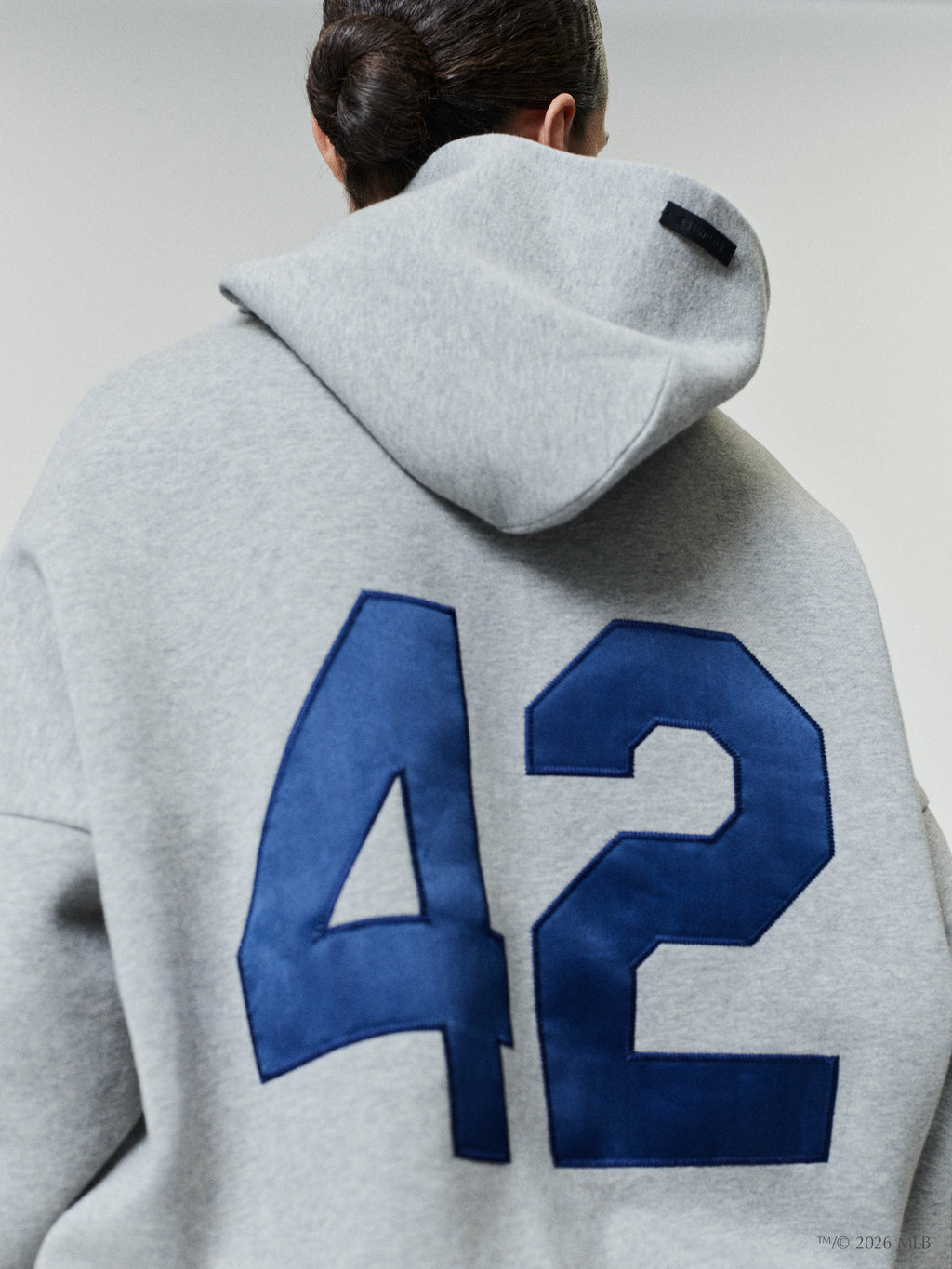 Rear view of gray hoodie with large blue "42" applique on the back and a black label on the hood panel
