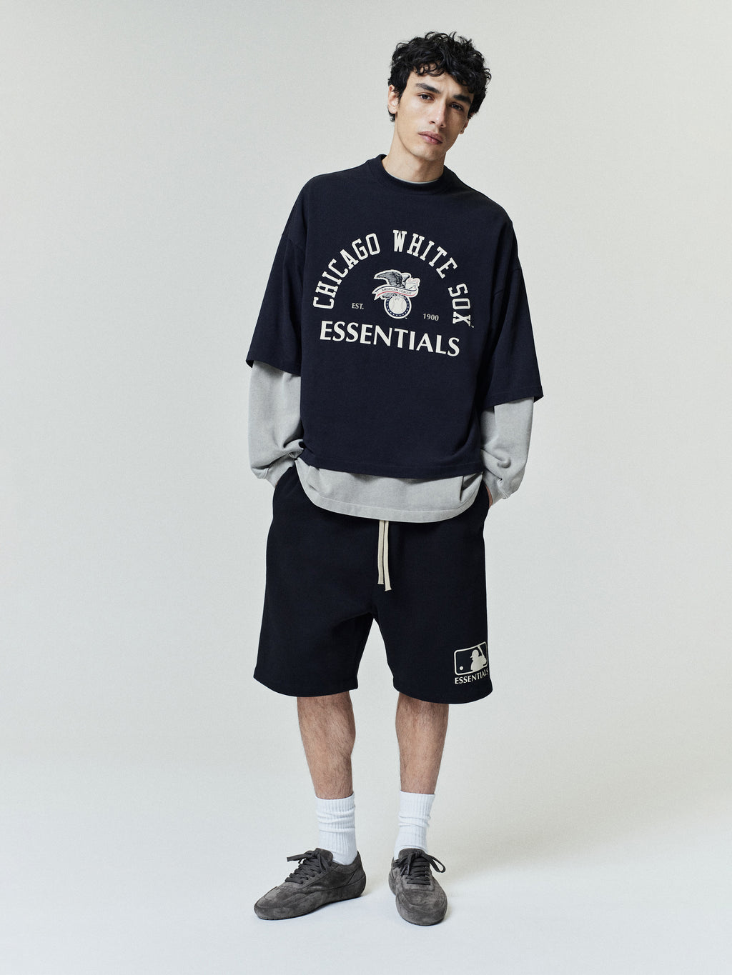 Model wearing the White Sox Al Merch Tee in navy with layered long sleeves and a relaxed fit, paired with black drawstring shorts and casual sneakers for a streetwear-inspired look.