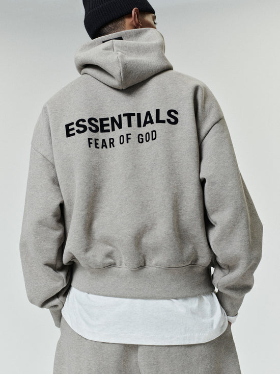 Person wearing a light gray oversized hoodie with black 