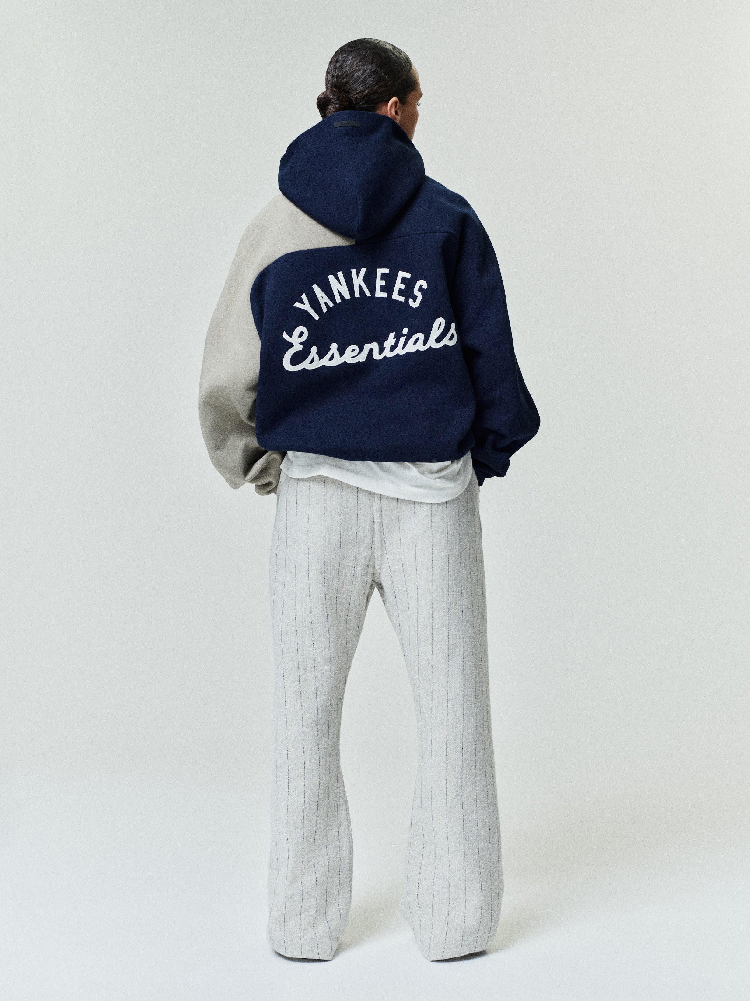 Rear view of Yankees Raglan Half Zip Sport Hoodie in navy and beige, featuring large white "YANKEES Essentials" script embroidery on a soft hooded outerwear top.