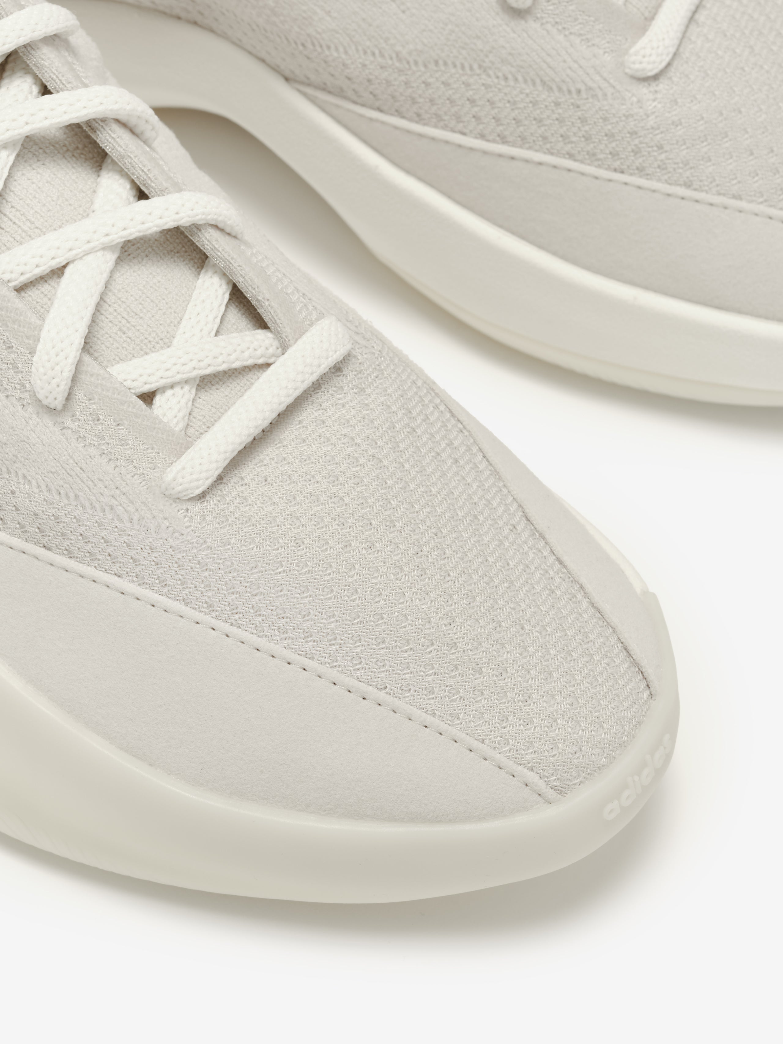 Close-up of light gray sneakers with white laces on a white background