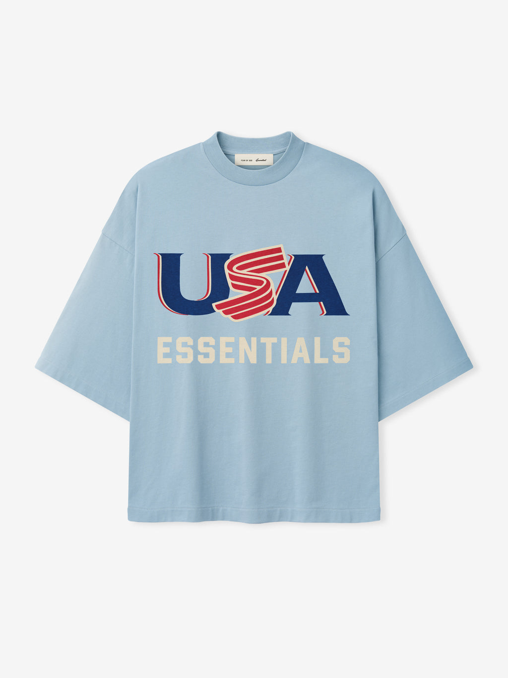 Light blue oversized short-sleeve T-shirt with bold red, white, and blue "USA" and cream "ESSENTIALS" text on front center