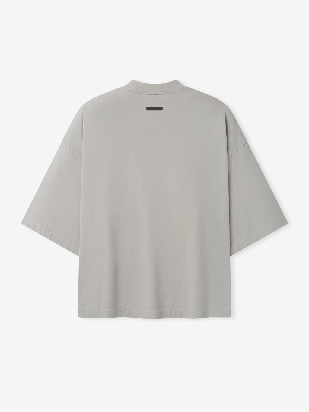 Back view of oversized light gray short-sleeve shirt with dropped shoulders and small black label near neckline