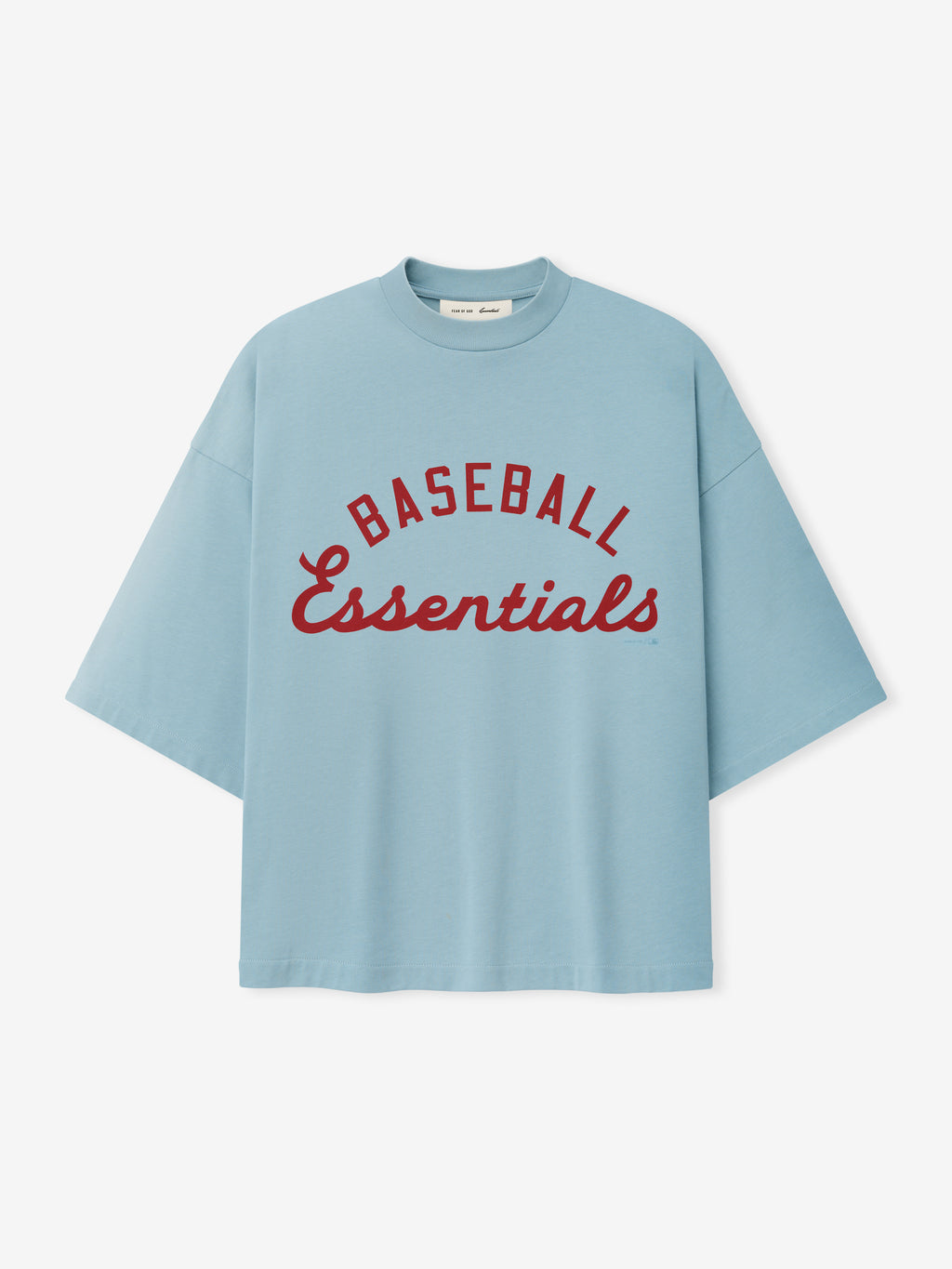 Mlb Merch Tee in soft stone blue featuring a relaxed fit with wide sleeves and bold red script lettering that reads "Baseball Essentials" across the chest on a casual top.