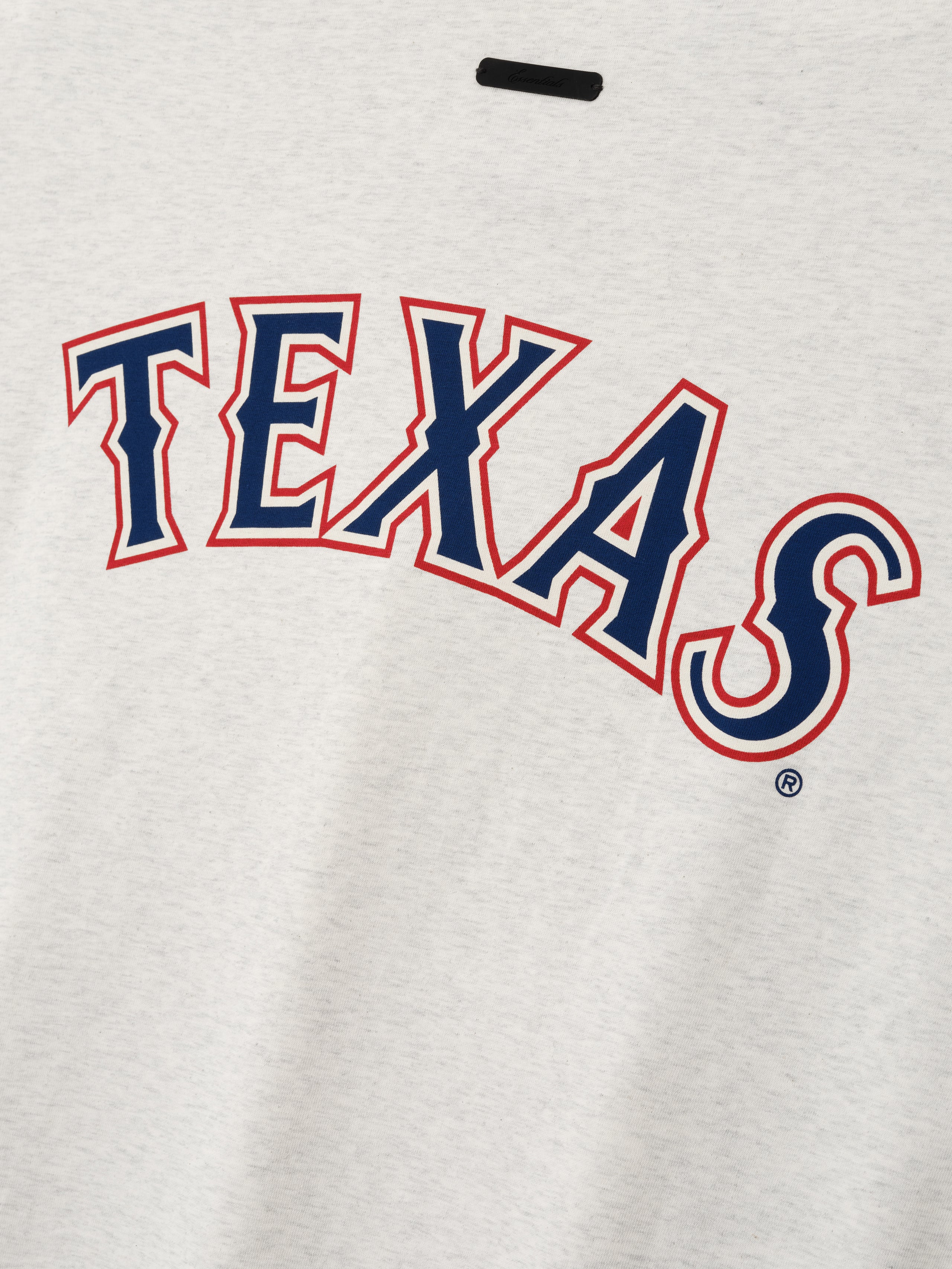 Close-up of the Rangers Merch Tee in a light oatmeal shade showcasing bold navy and red "TEXAS" lettering printed on soft cotton fabric, designed as a casual top.