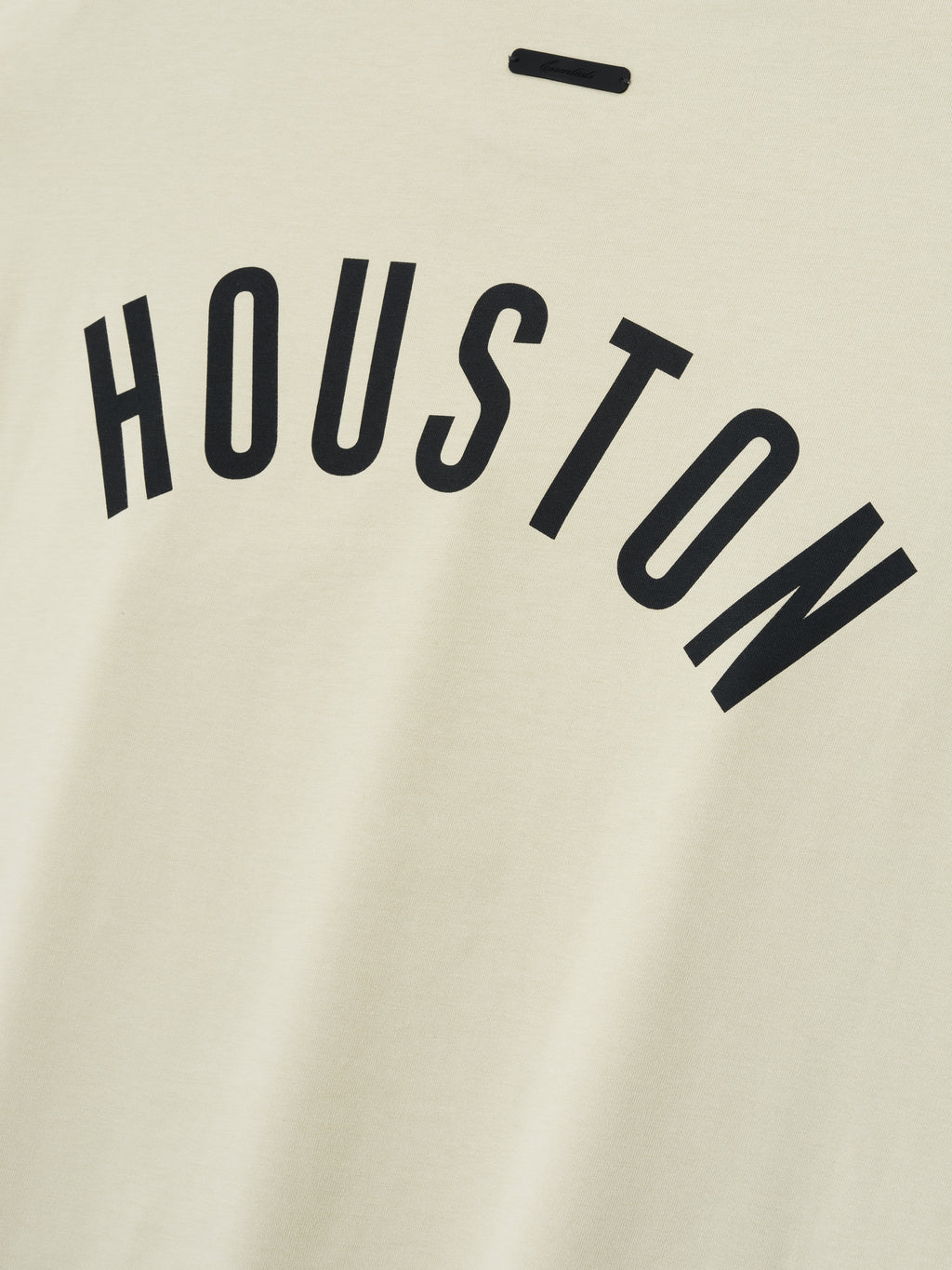 Close-up of Astros Merch Tee in a light sandstone color featuring bold black "HOUSTON" lettering arched across a soft cotton fabric for a casual top option.