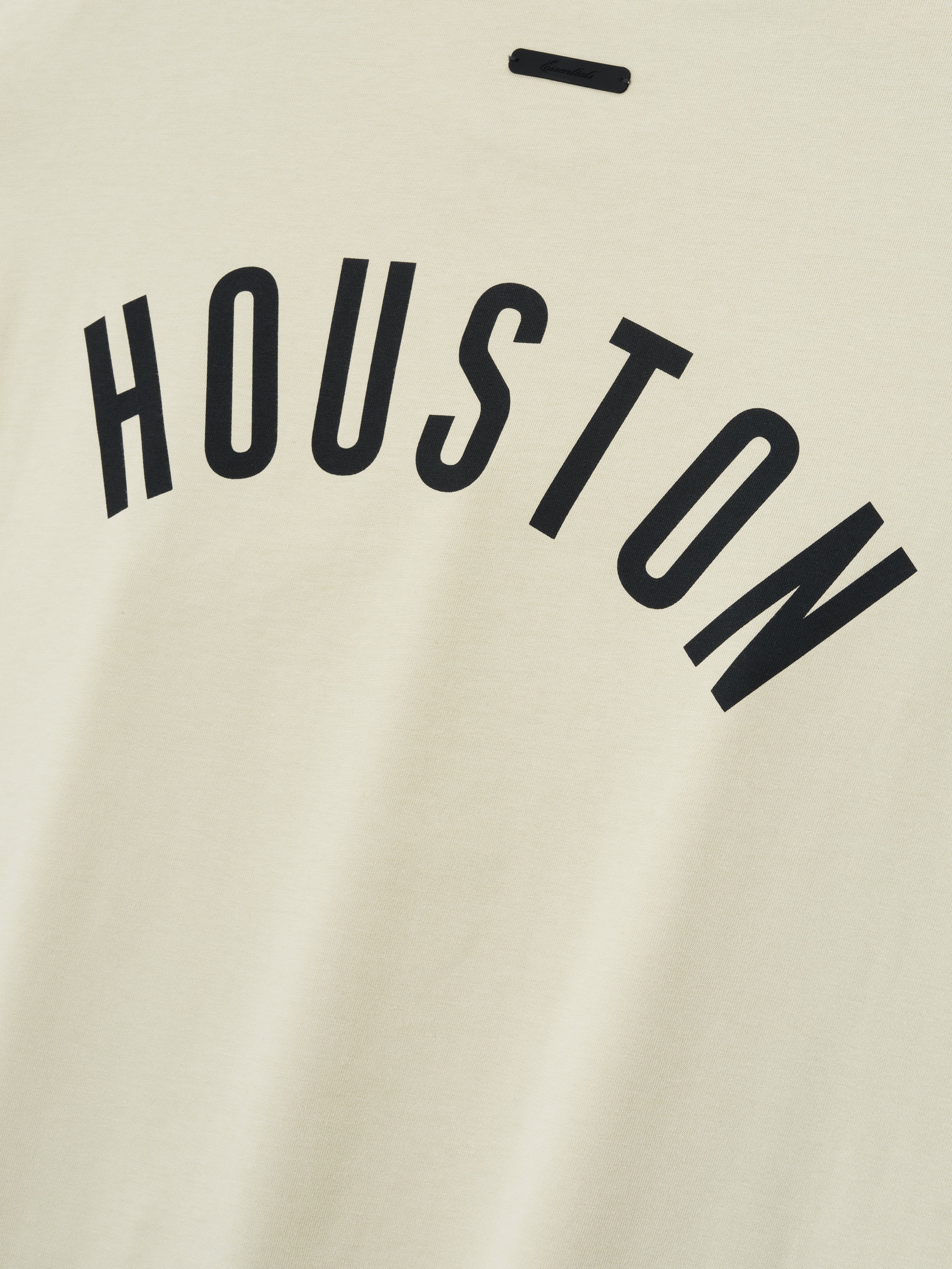 Close-up of Astros Merch Tee in a light sandstone color featuring bold black "HOUSTON" lettering arched across a soft cotton fabric for a casual top option.