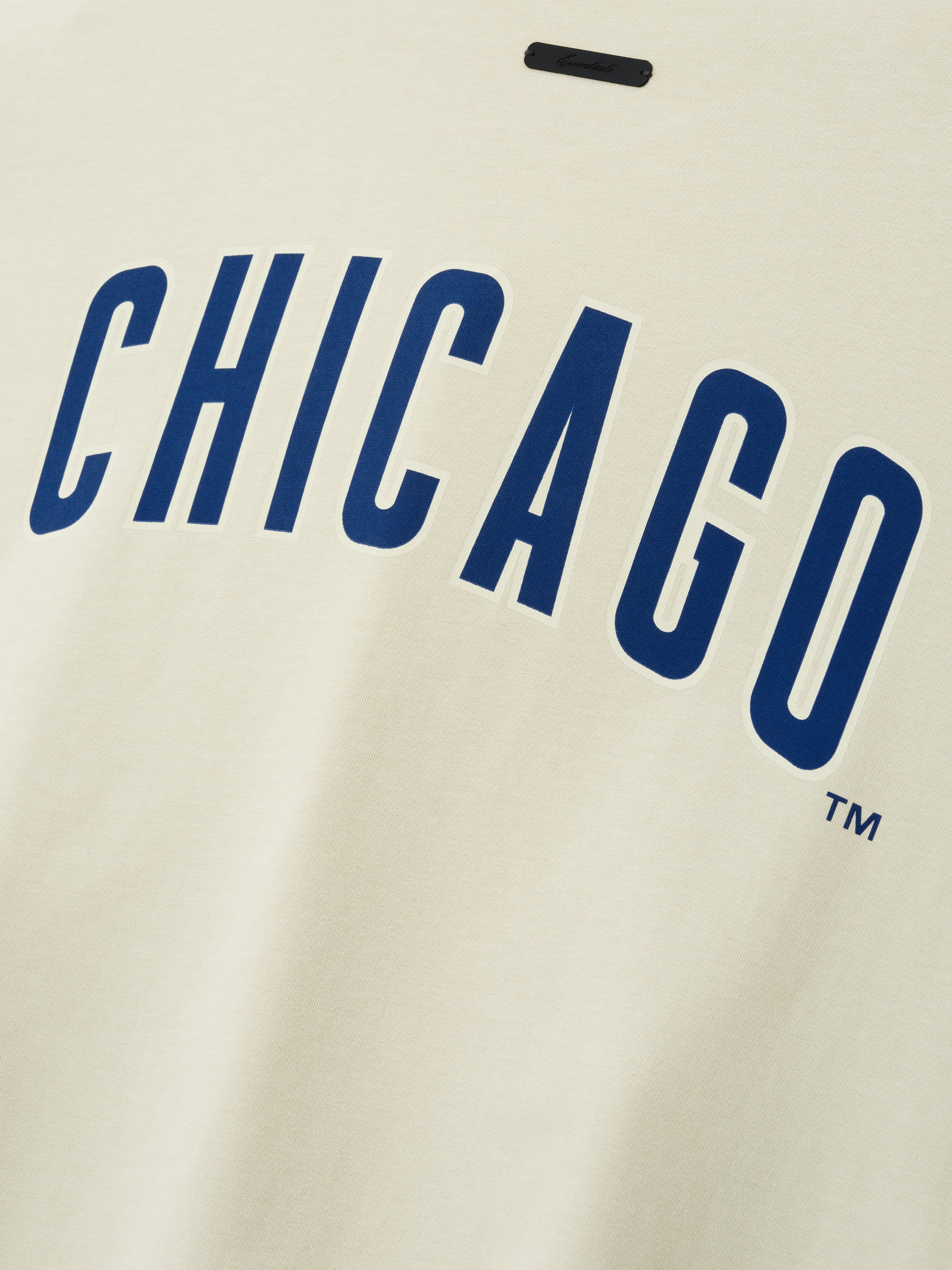Cubs Merch Tee in a soft sandstone tone with bold navy blue "CHICAGO" text in a tall, clean font across the chest on a comfortable cotton top.