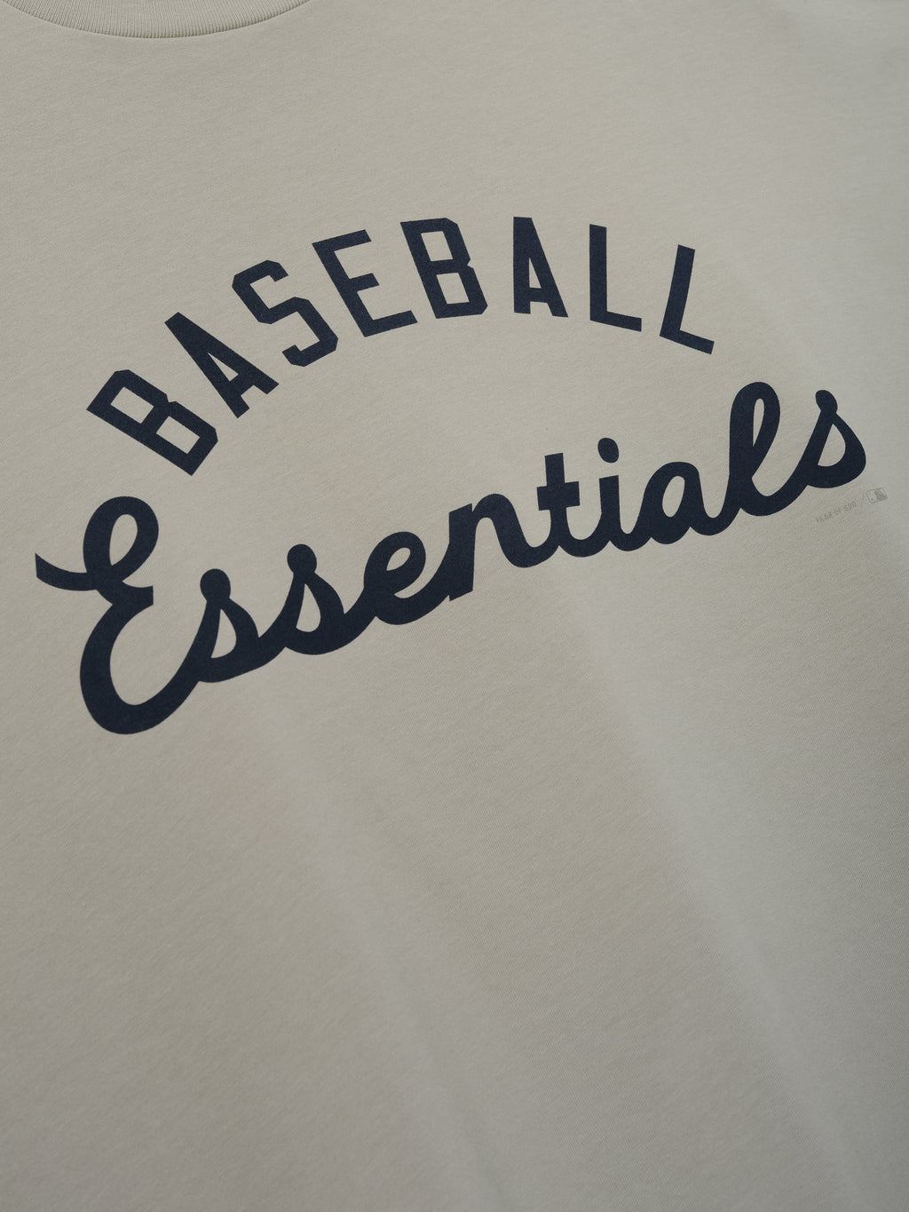 MLB Boxy Long Sleeve Tee in a soft oyster shade featuring navy "Baseball Essentials" script in an arch design on smooth fabric, perfect for casual tops.