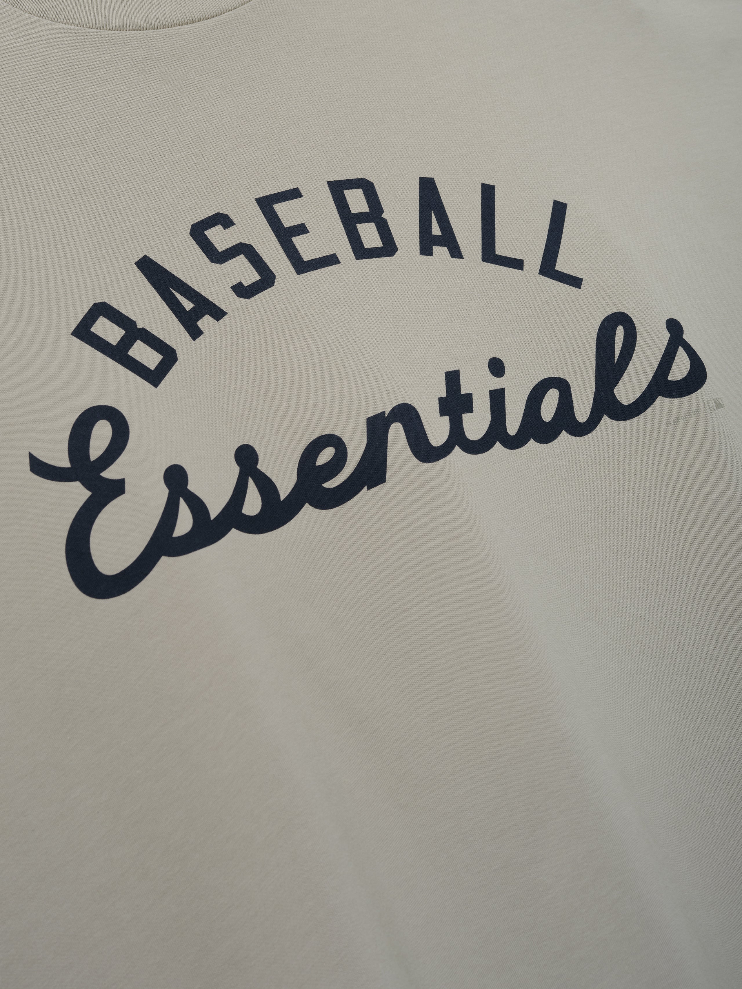 MLB Boxy Long Sleeve Tee in a soft oyster shade featuring navy "Baseball Essentials" script in an arch design on smooth fabric, perfect for casual tops.