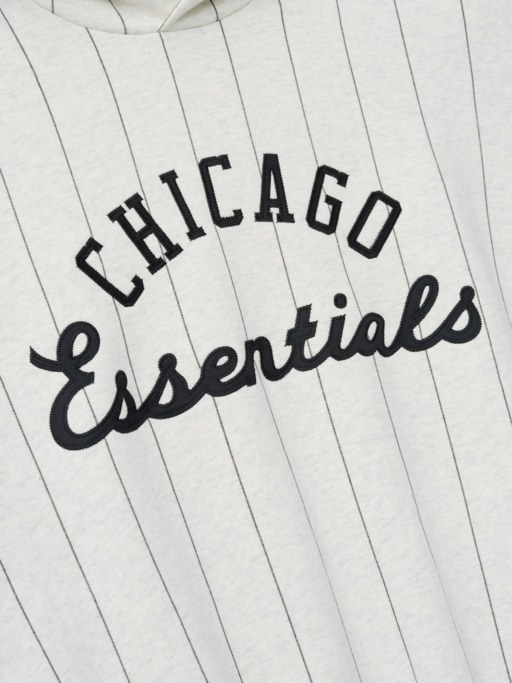 Close-up of the front of White Sox Sport Hoodie in oatmeal heather with thin black pinstripes and black embroidered "Chicago Essentials" text across the chest.