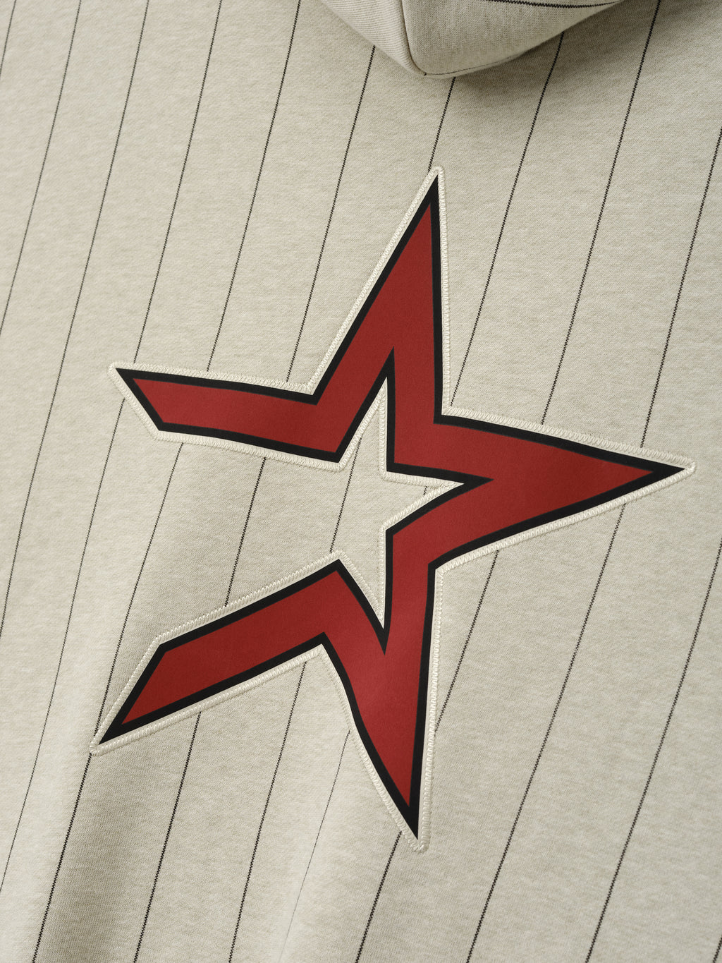 Close-up of Astros Sport Hoodie in a light stone shade with thin black pinstripes, featuring a large red star graphic with white outline on soft outerwear fabric.
