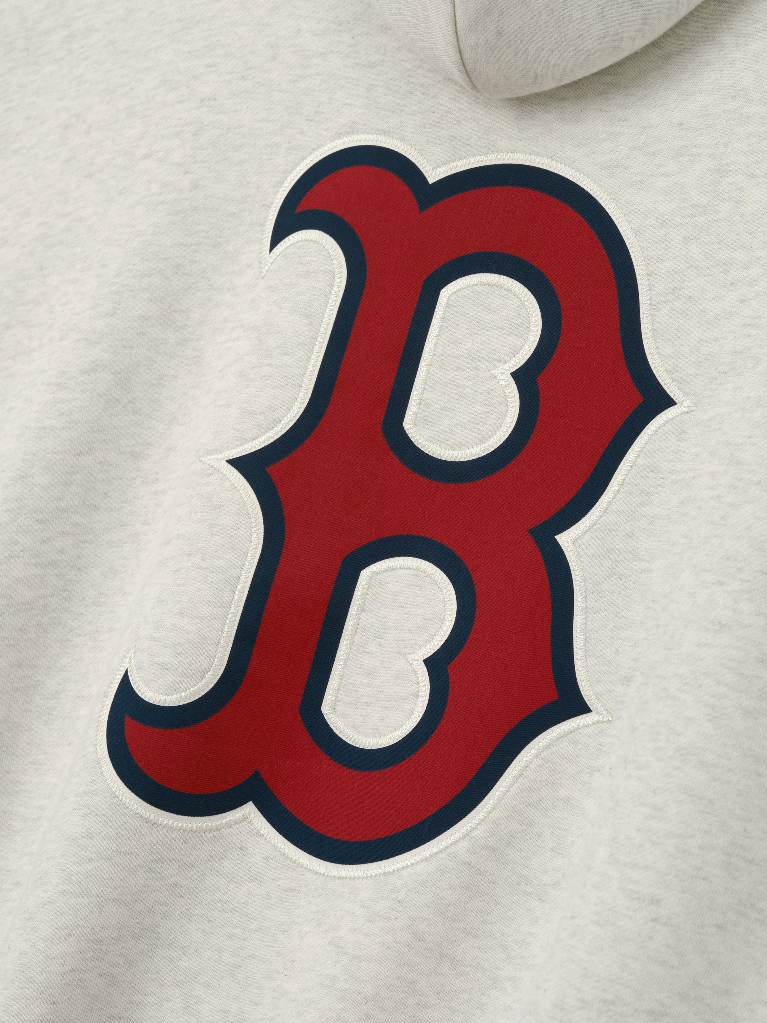 Close-up of Red Sox Sport Hoodie in a light oatmeal heather fabric featuring a large red and navy Boston "B" logo appliqué on soft, casual outerwear material.