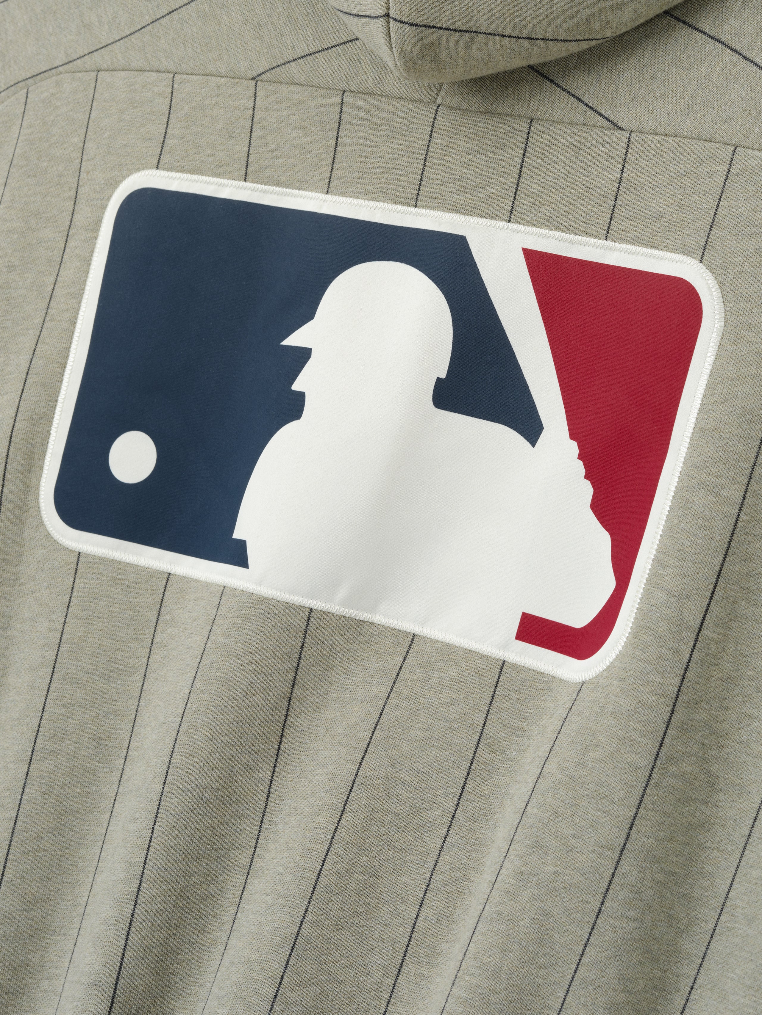 MLB Raglan Sport Hoodie in muted seal heather with thin vertical black pinstripes, featuring a large white baseball batter silhouette logo on a navy and red background on soft outerwear fabric.