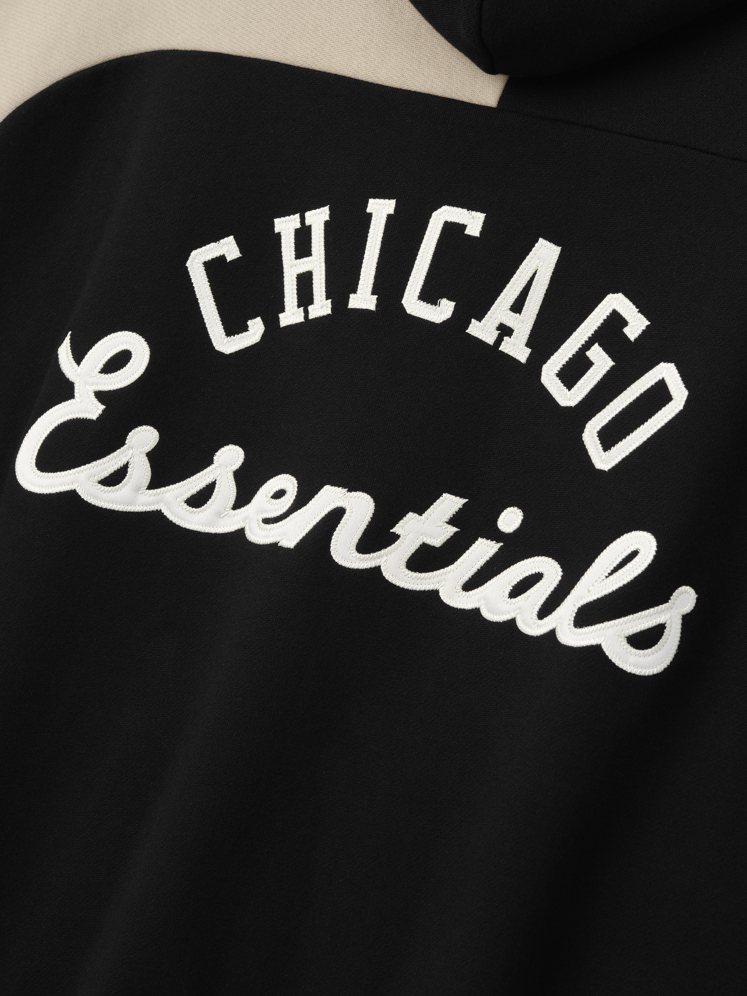 Close-up of the back of the White Sox Raglan Half Zip Sport Hoodie in black, featuring textured white embroidered "Chicago Essentials" script for a stylish outerwear detail.