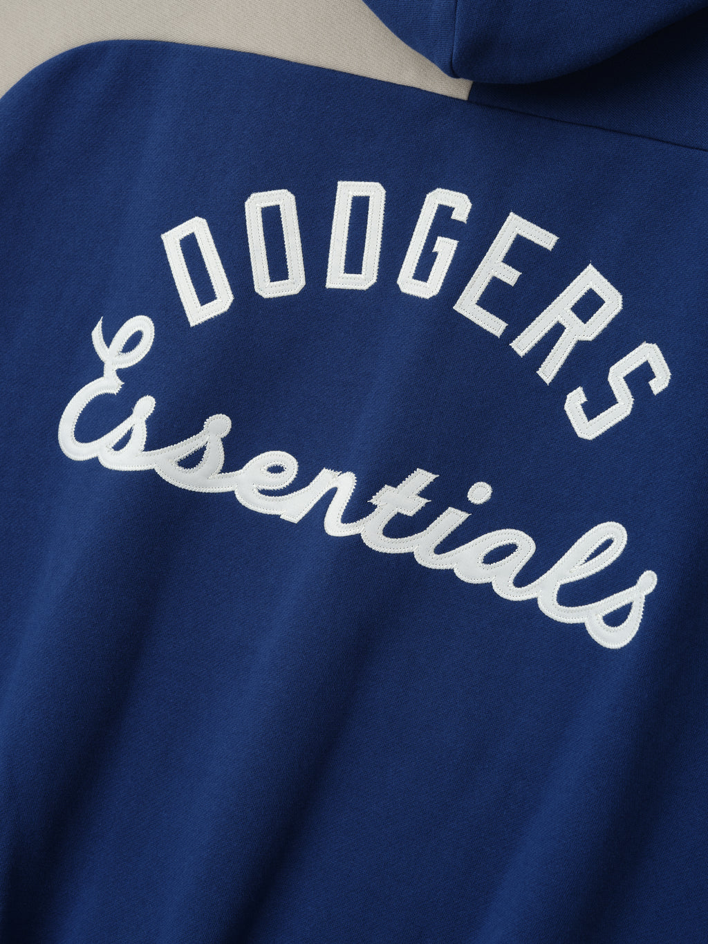 Back view close-up of Dodgers Raglan Half Zip Sport Hoodie in blue fabric featuring white embroidered "Dodgers Essentials" text in block and script fonts.