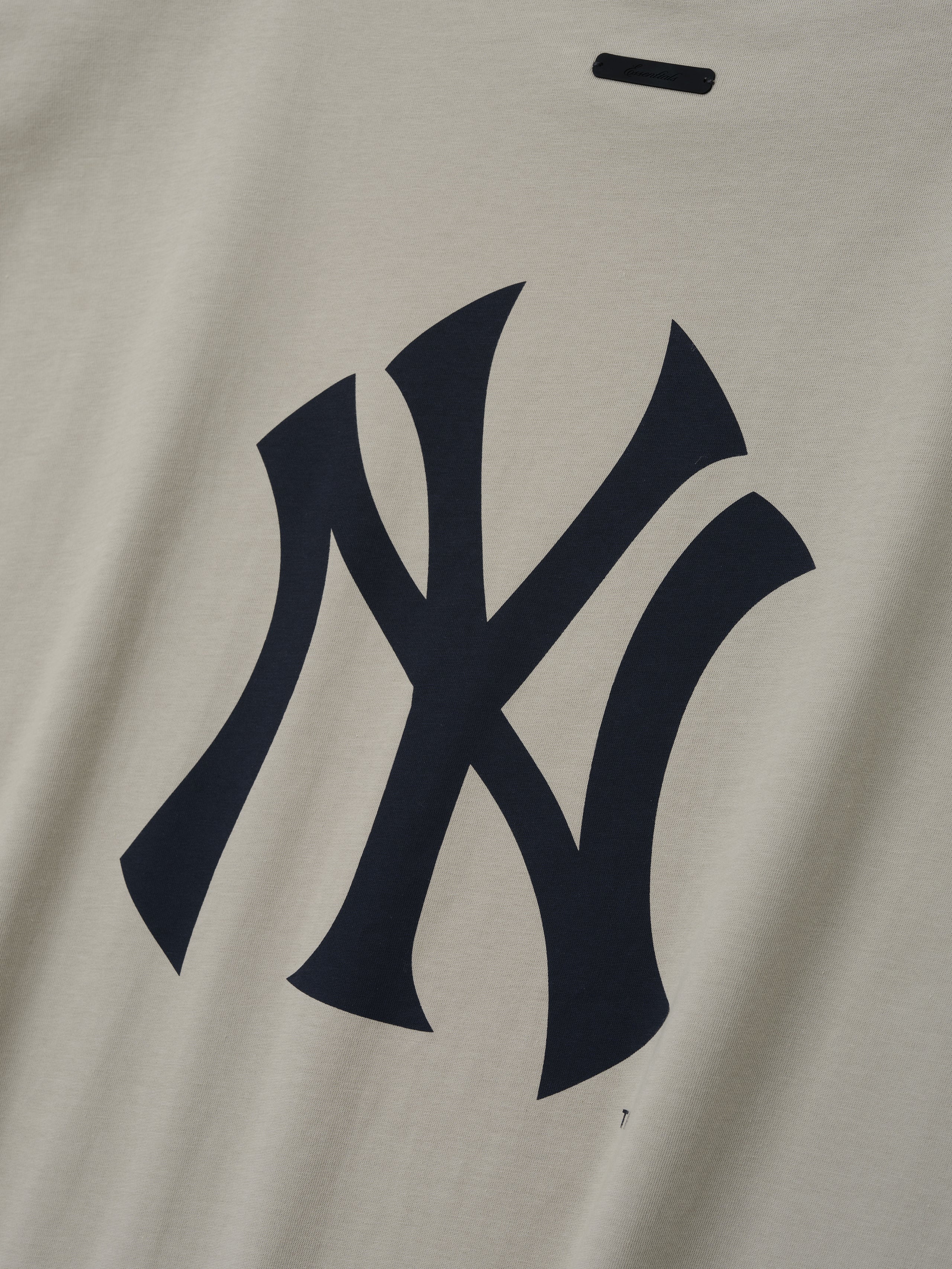 Yankees 90s Cut Off featuring a bold navy Yankees logo printed on soft beige cotton fabric, highlighting a vintage-inspired design for a casual, timeless look.
