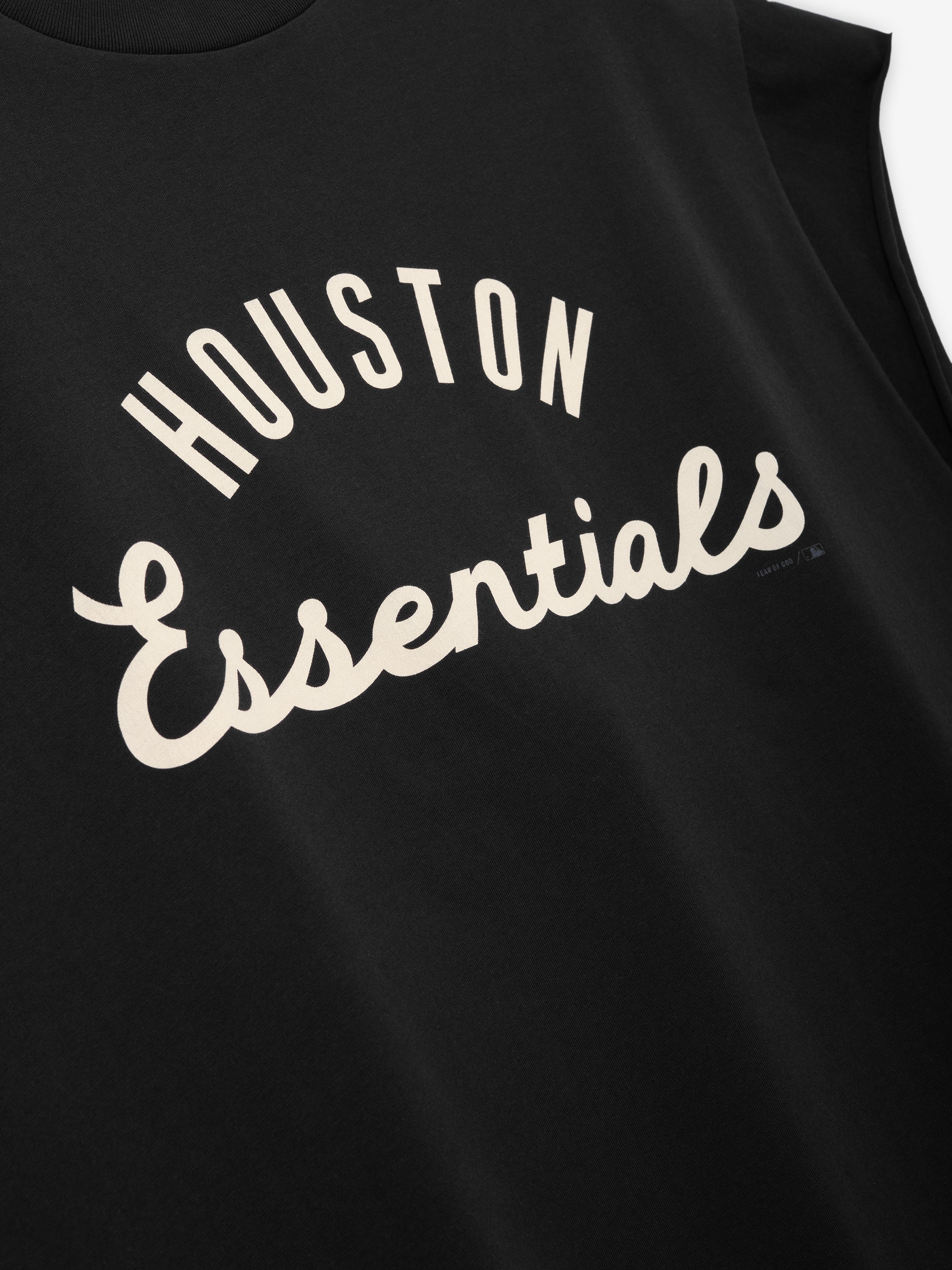 Close-up of a black sleeveless top displaying cream-colored text "Houston Essentials" in a curved design on the front, part of the Astros 90s Cut Off collection.