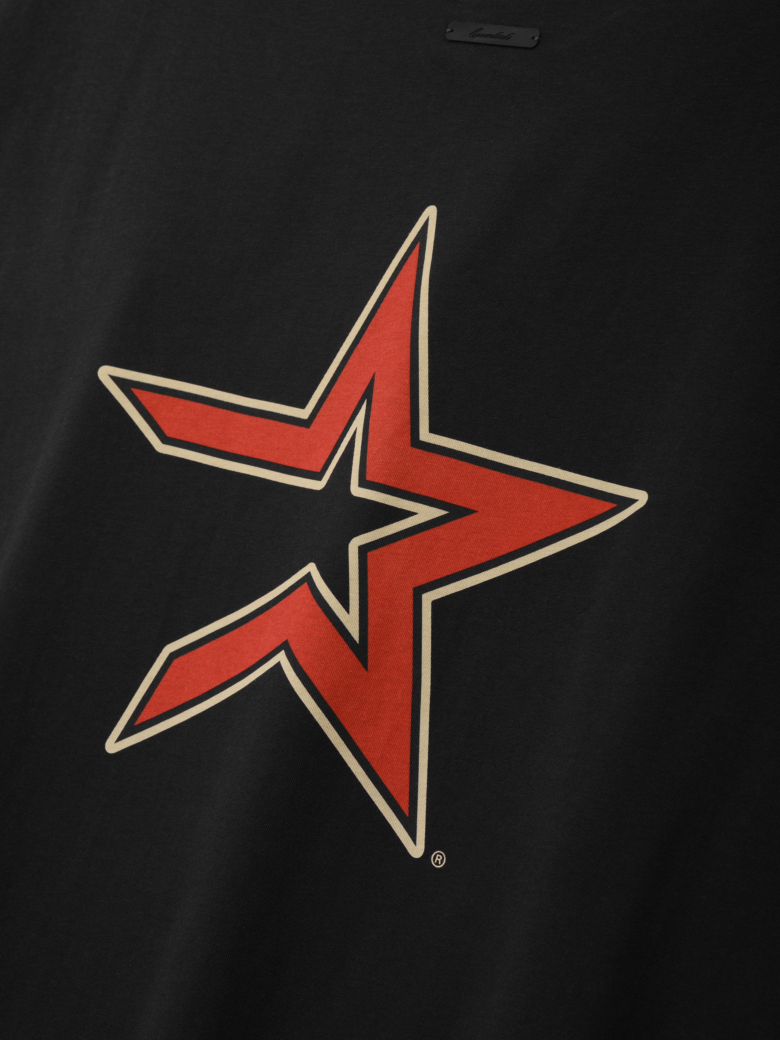 Close-up of a black fabric featuring a bold red and beige outlined star graphic with sharp angles, part of the Astros 90s Cut Off collection.