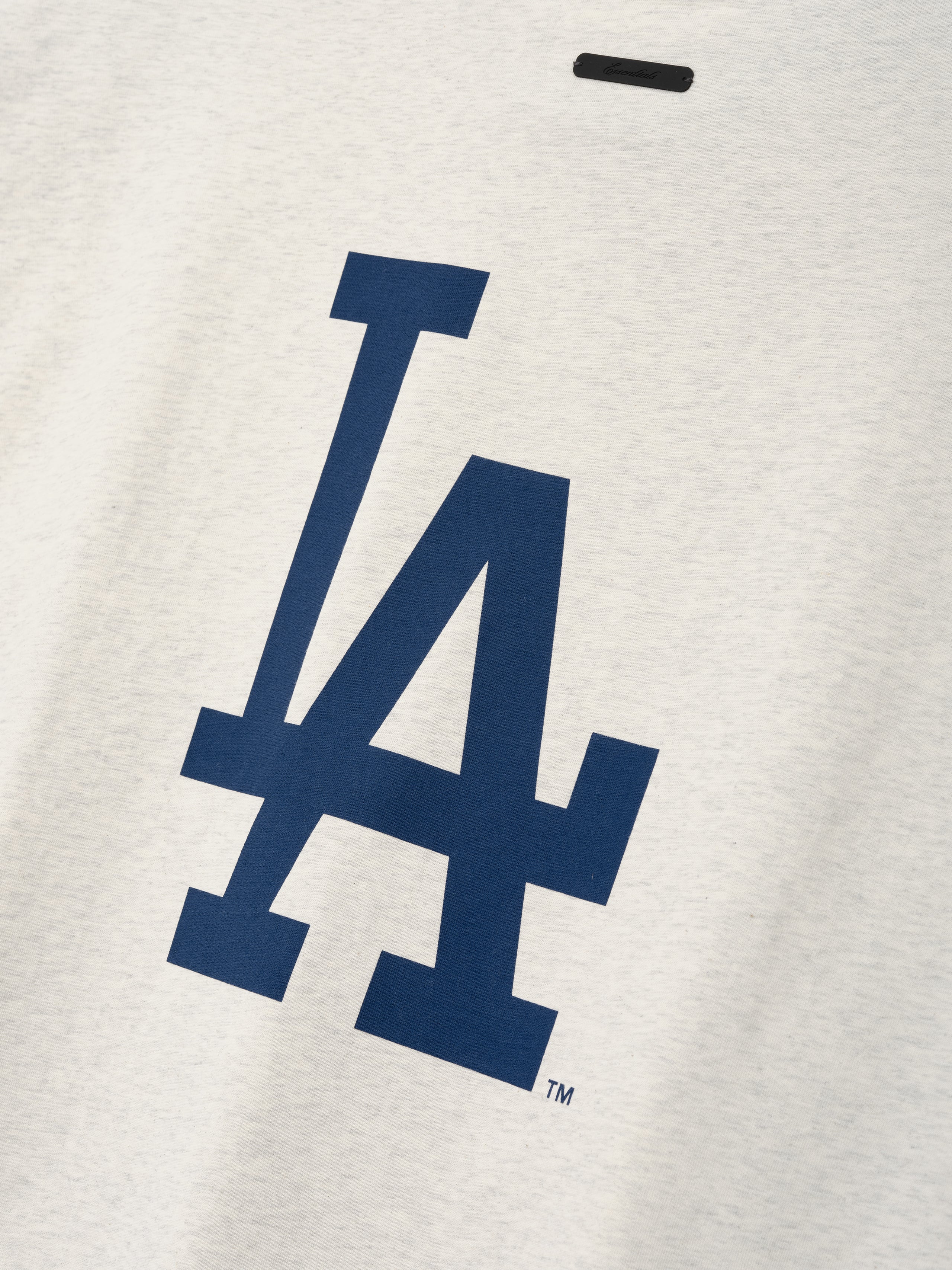 Close-up of a navy blue LA logo printed on soft oatmeal heather fabric from the Dodgers 90s Cut Off top, showcasing clean lines and smooth texture.
