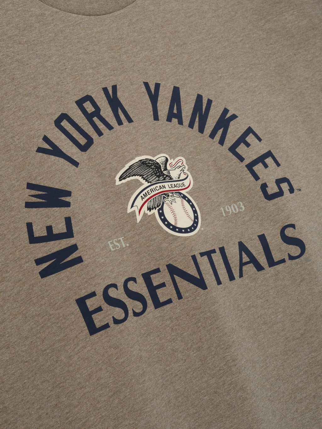 Yankees AL Merch Tee in soft brown heather fabric featuring bold navy "New York Yankees Essentials" text and a vintage American League eagle graphic on a casual top.