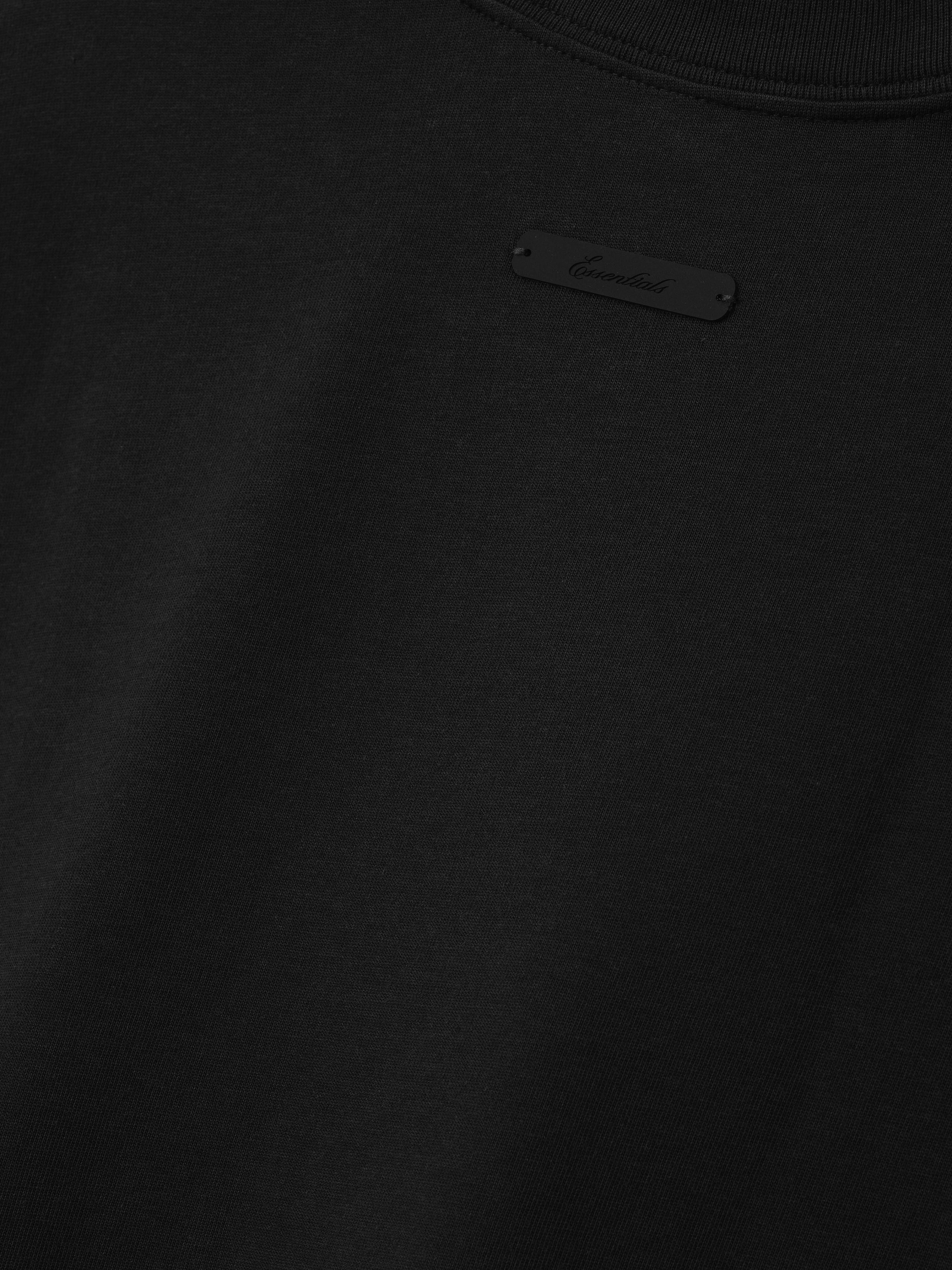 Close-up of the White Sox AL Merch Tee in black, showcasing a subtle tonal label detail on smooth cotton fabric, highlighting its minimalist streetwear design.