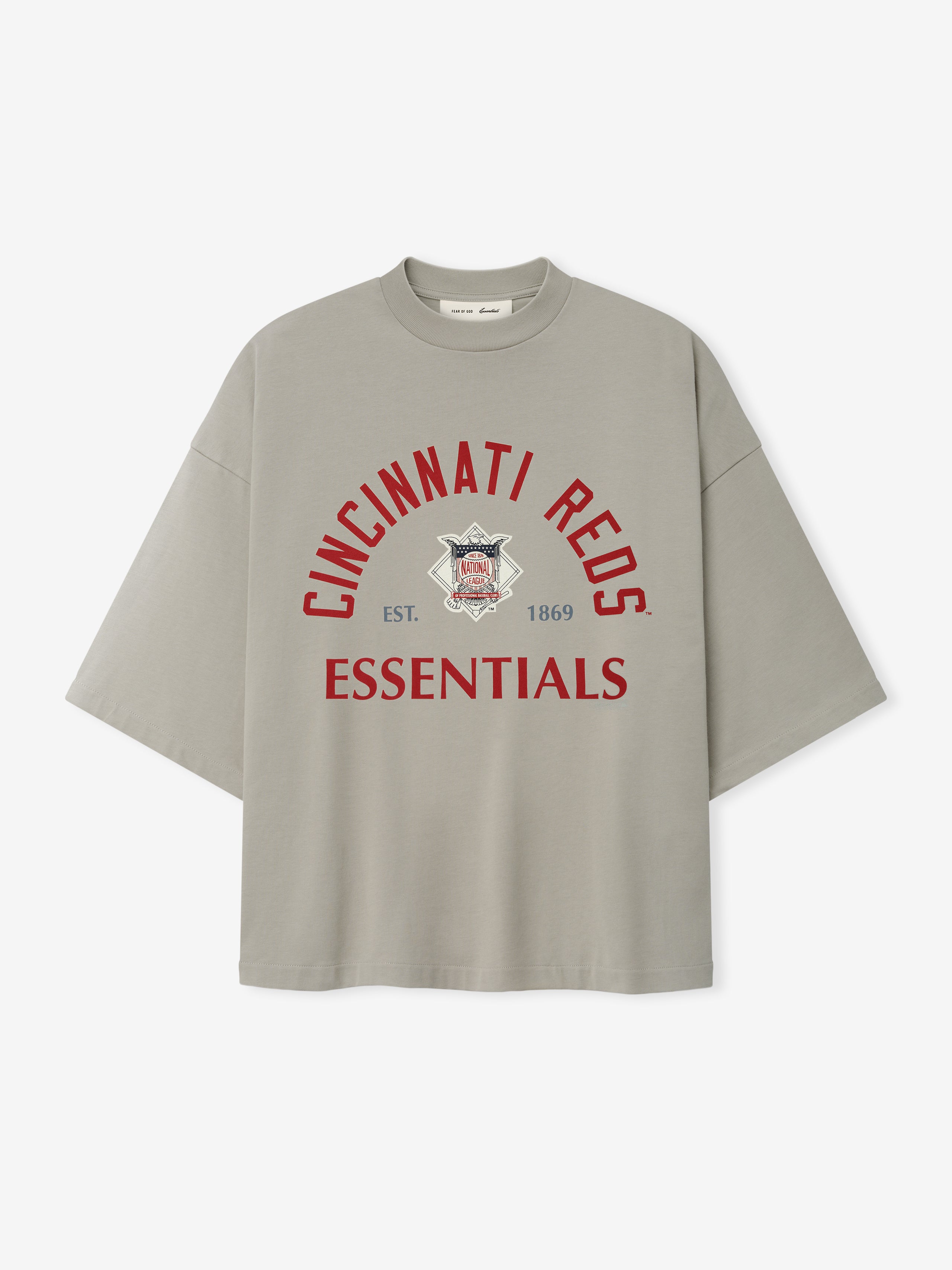 Reds NL Merch Tee in a muted taupe shade featuring relaxed fit with dropped shoulders and bold red "Cincinnati Reds Essentials" text above a vintage-inspired logo on soft fabric.