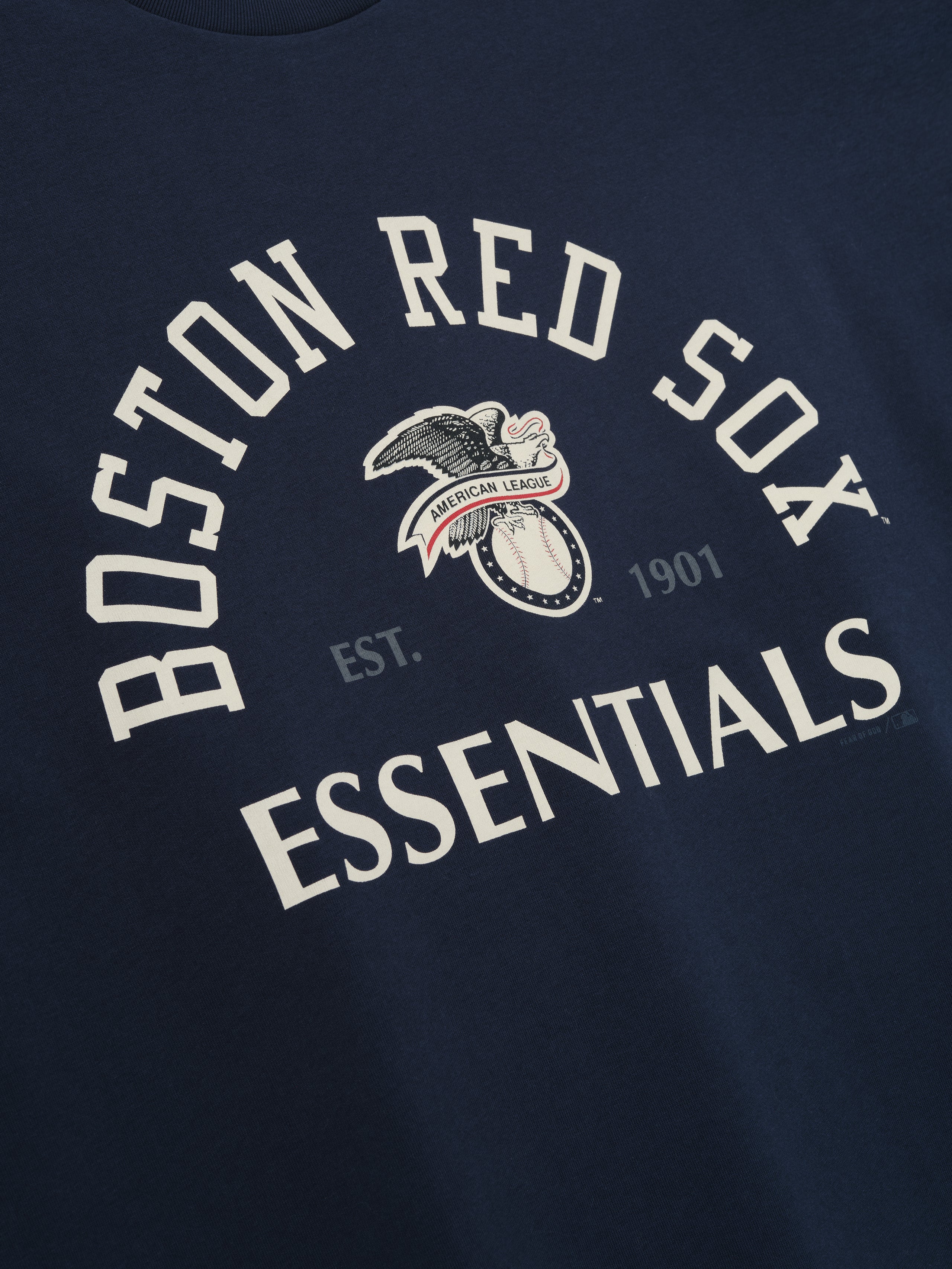 Red Sox AL Merch Tee in dark sapphire with curved "Boston Red Sox Essentials" text and vintage-style eagle and baseball graphic on soft fabric top.
