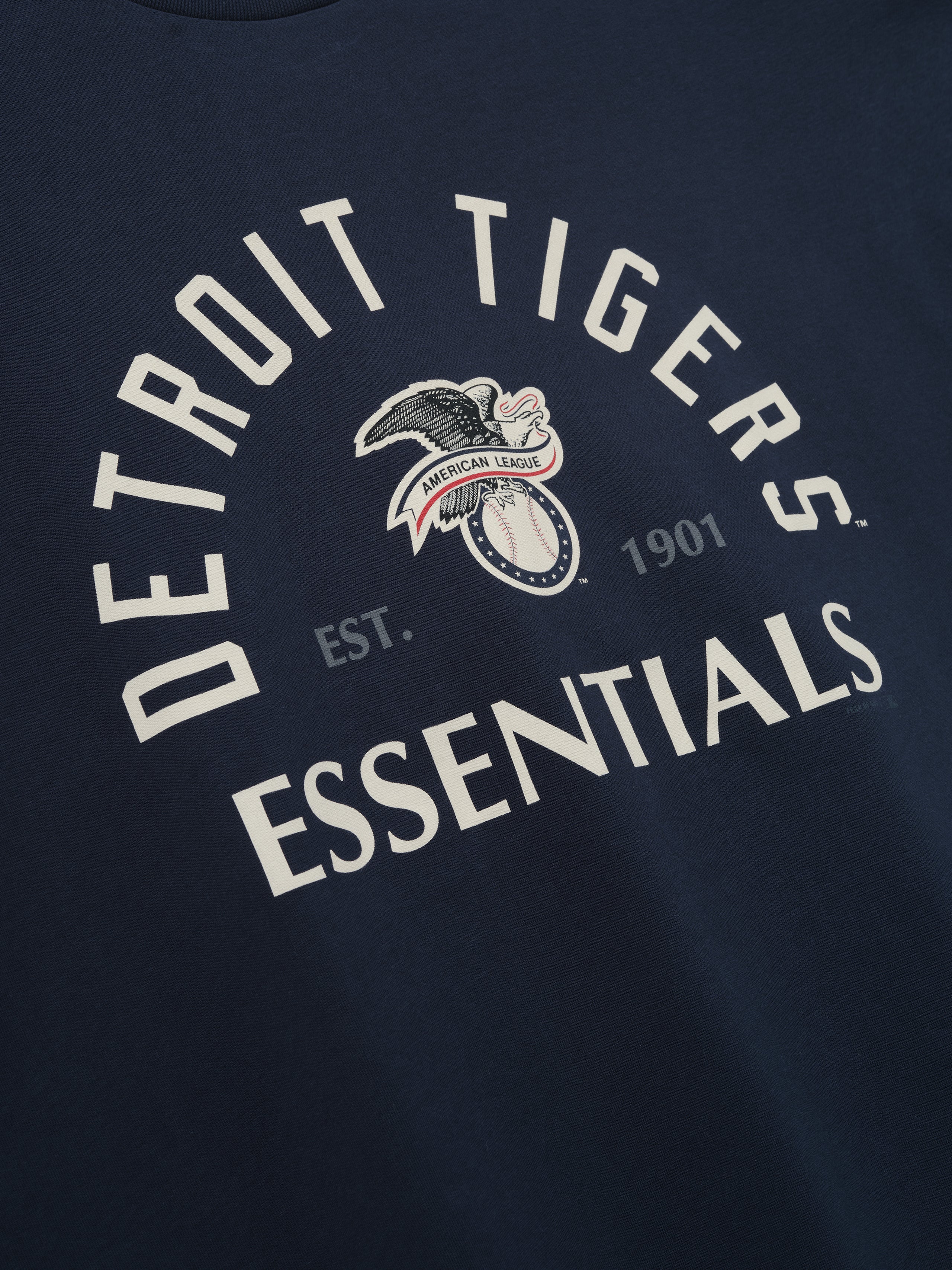 Tigers AL Merch Tee in a deep sapphire shade featuring bold vintage "Detroit Tigers Essentials" text with an eagle and baseball emblem and "American League" banner on soft fabric.