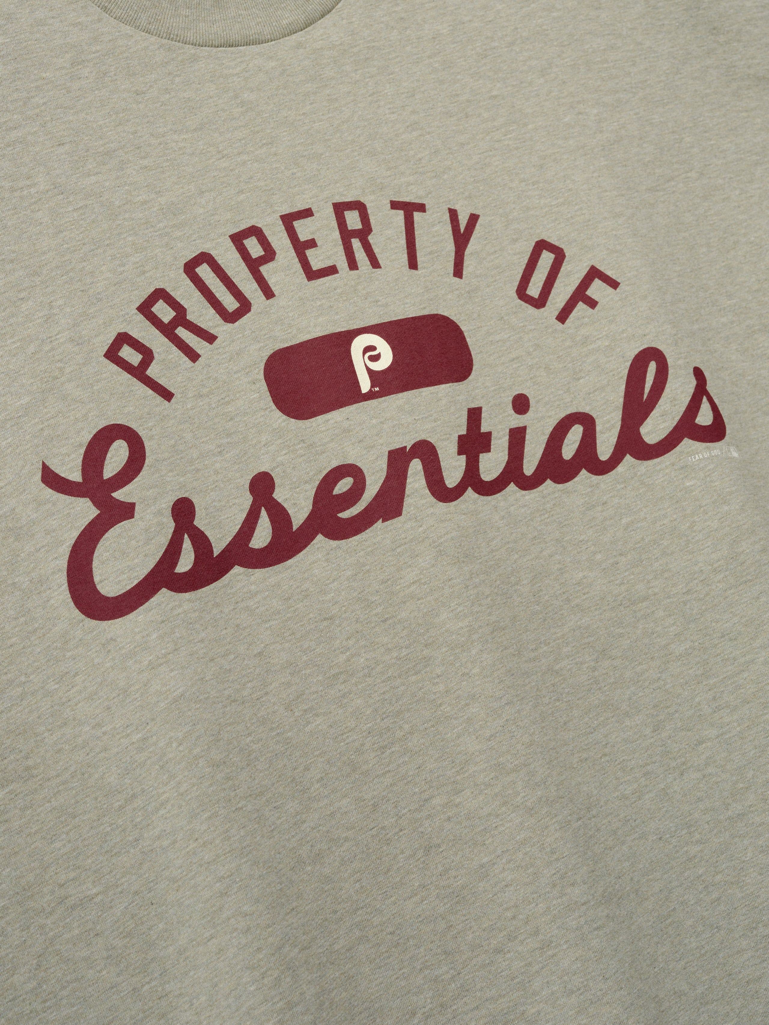 Phillies Merch Tee in a muted light gray fabric featuring maroon "Property of Essentials" text and a vintage logo centered on the chest, designed for casual everyday wear.