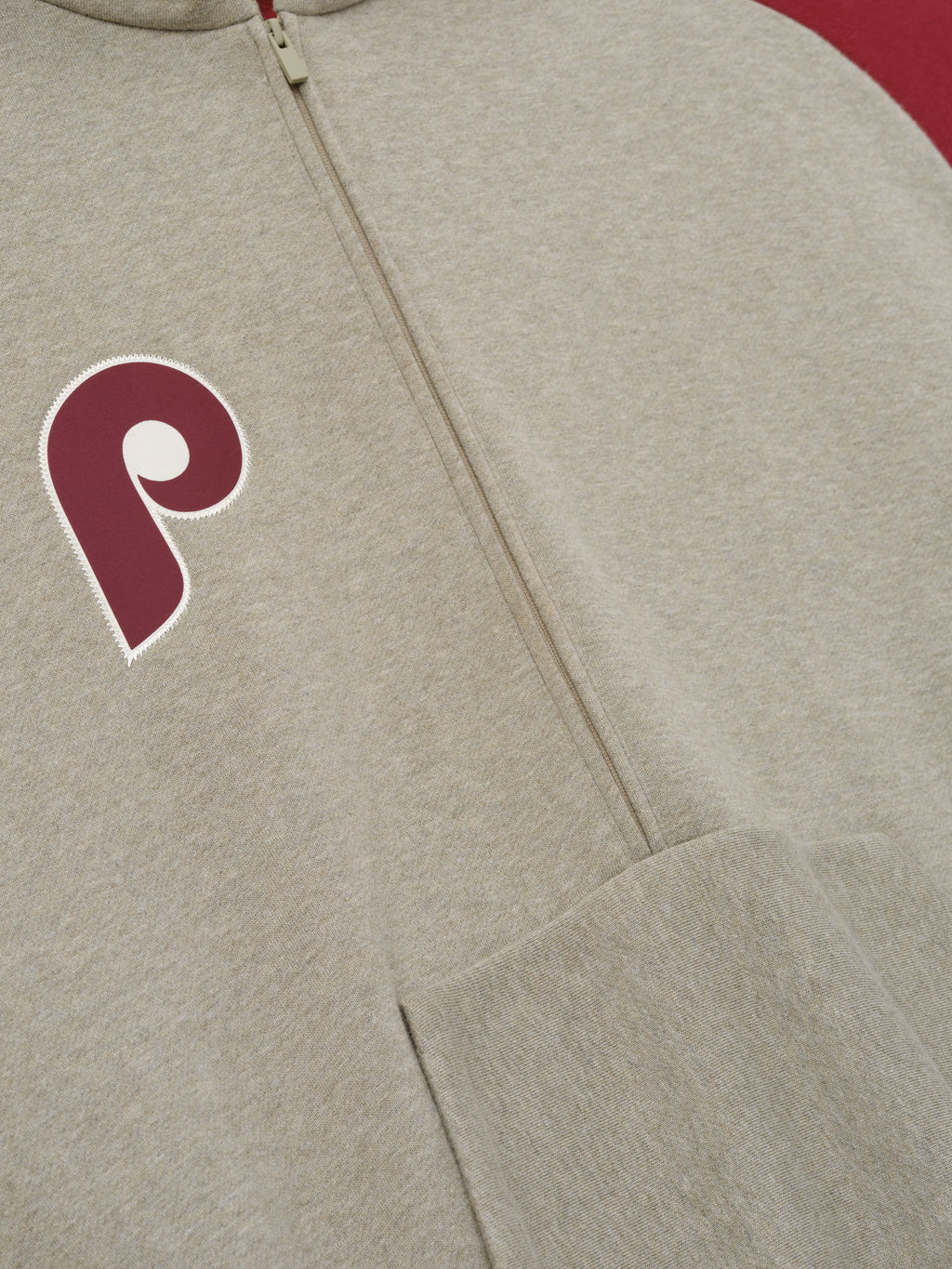 Phillies Raglan Half Zip Sport Hoodie in a soft heathered beige fabric with a half-zip front and contrasting deep red sleeve, featuring a maroon Phillies "P" emblem on the chest.
