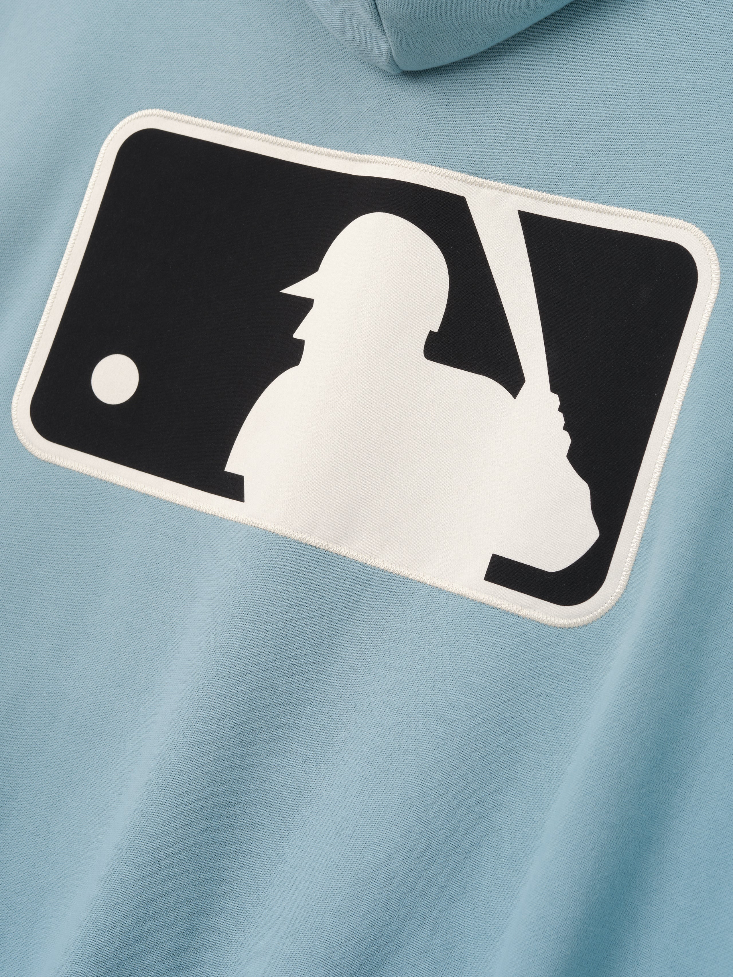 Close-up of the back of Mlb Full Zip Sport Hoodie in muted stone blue featuring a large contrasting white and black baseball batter logo patch with clean edge detailing.