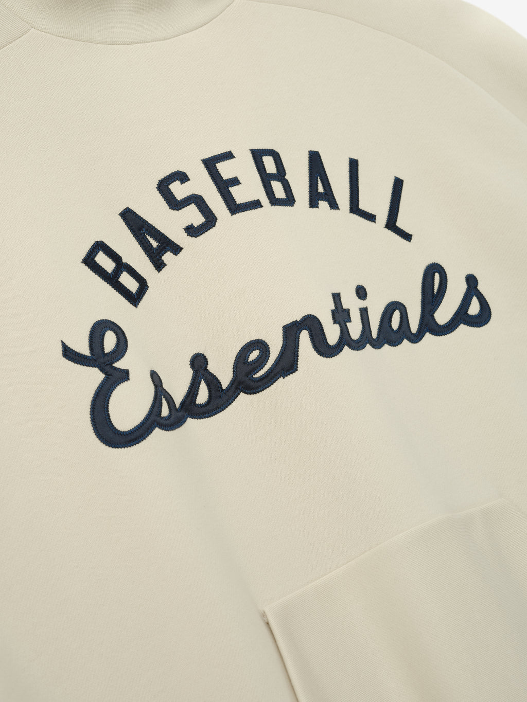 Mlb Sport Crewneck in a soft oat shade featuring navy "Baseball Essentials" embroidered text across the chest and a front kangaroo pocket for casual layering.