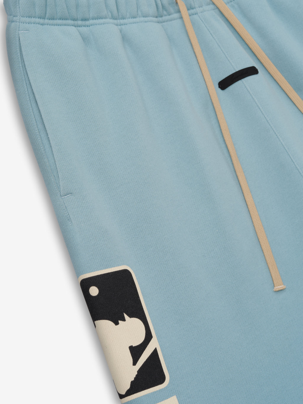Mlb Lounge Sweatpant in soft stone blue featuring an elastic waistband with beige drawstrings and a contrasting black and cream graphic near the pocket on casual bottoms.
