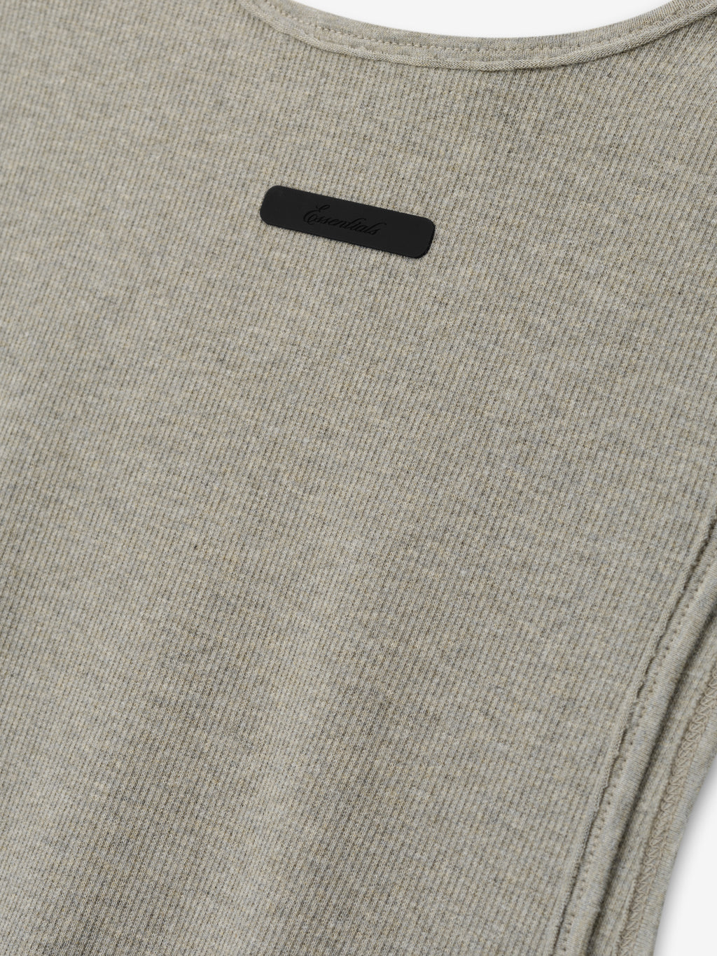 Ribbed Essential Tank in a soft seal heather tone, featuring a finely ribbed knit fabric with clean, subtle stitching and a small tonal logo plaque near the neckline for understated detail.
