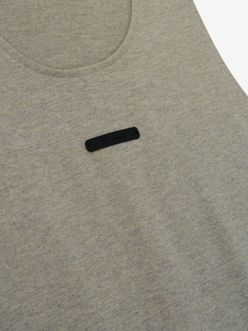 Essential Tank in a muted light gray heather fabric featuring a rounded neckline and a small black rectangular logo patch centered on the chest for a subtle, casual top.