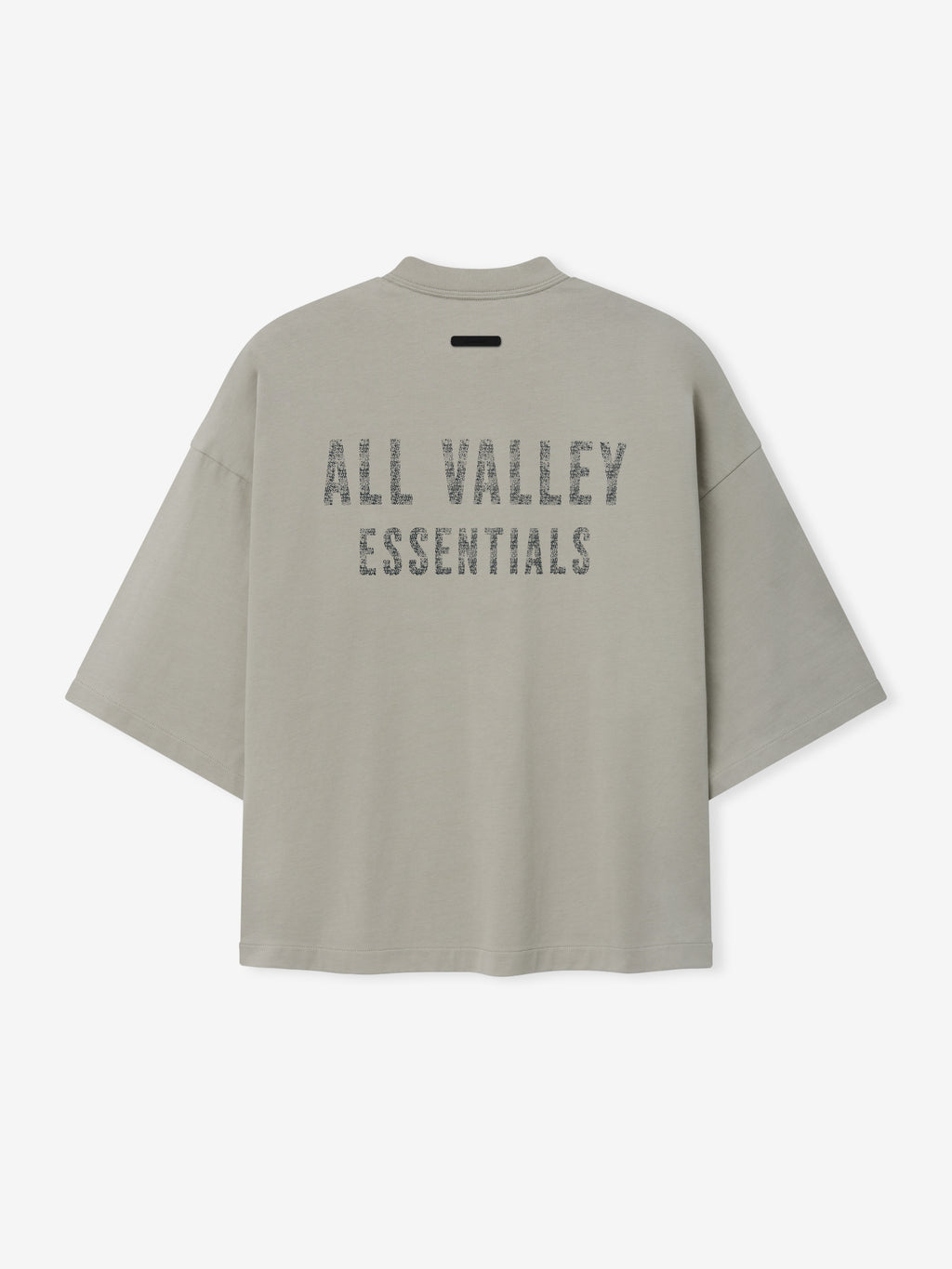 Merch Tee (Boxy) in muted seal grey with a relaxed oversized fit, featuring dropped shoulders and bold distressed all valley essentials text printed across the back for a casual streetwear look.