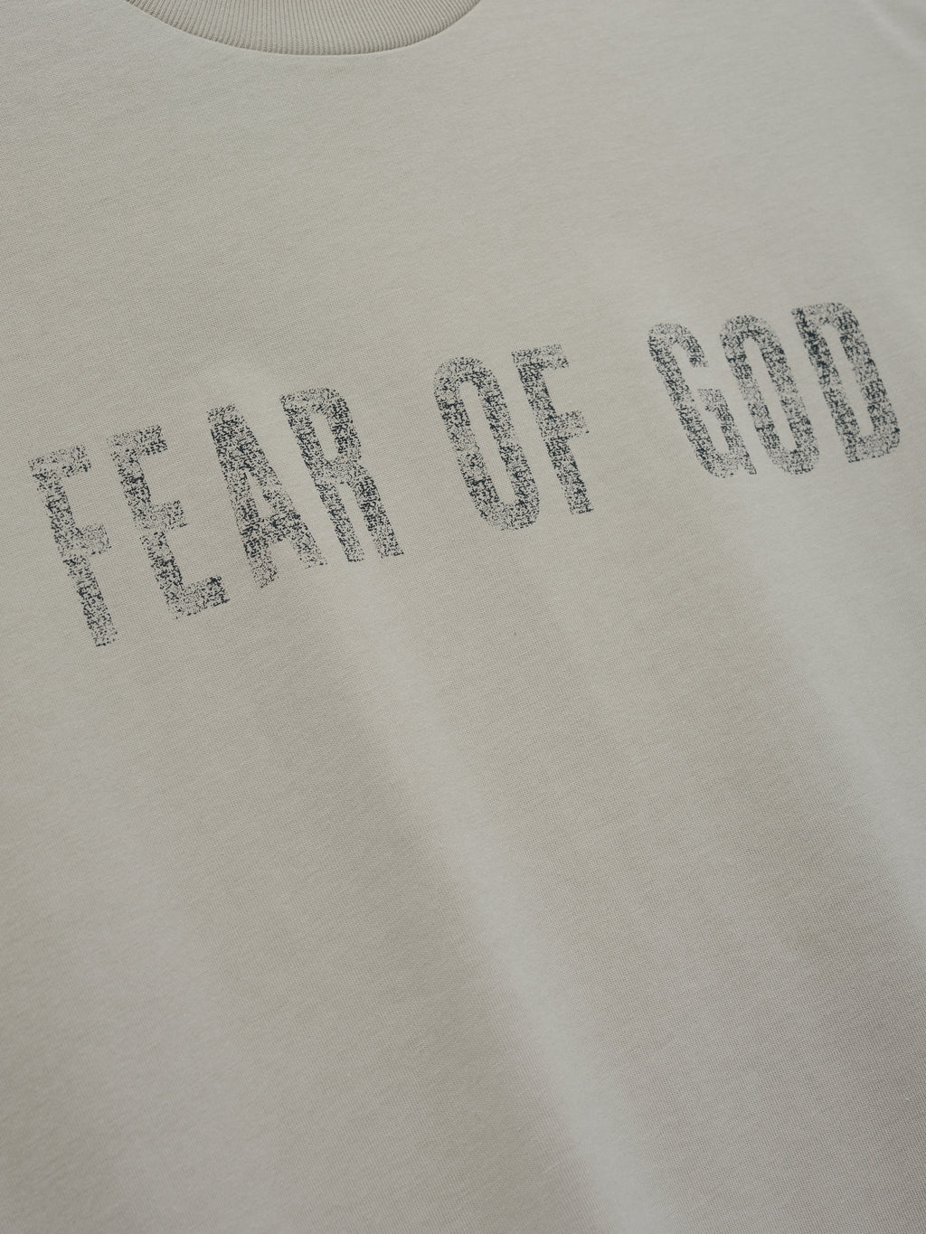 Merch Tee (Boxy) in a soft ivory shade with a relaxed fit, featuring distressed Fear of God lettering printed across the front for a subtle yet bold streetwear look.