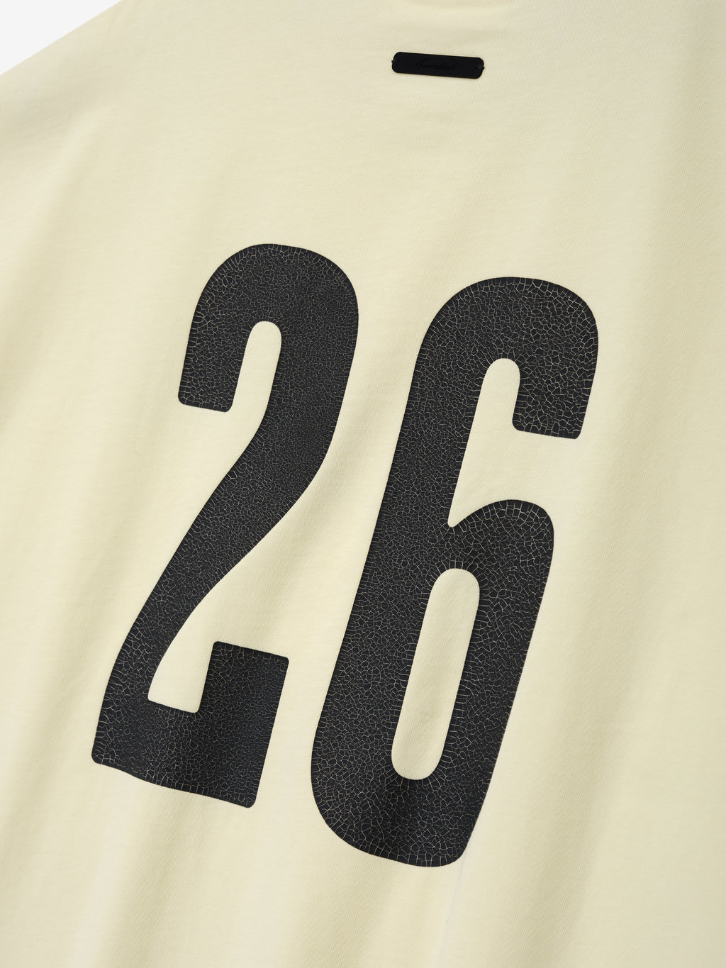Cut Off 90'S Tee in a soft pale cream color featuring a large black number 26 with a textured finish printed on the fabric, designed as a casual streetwear top.