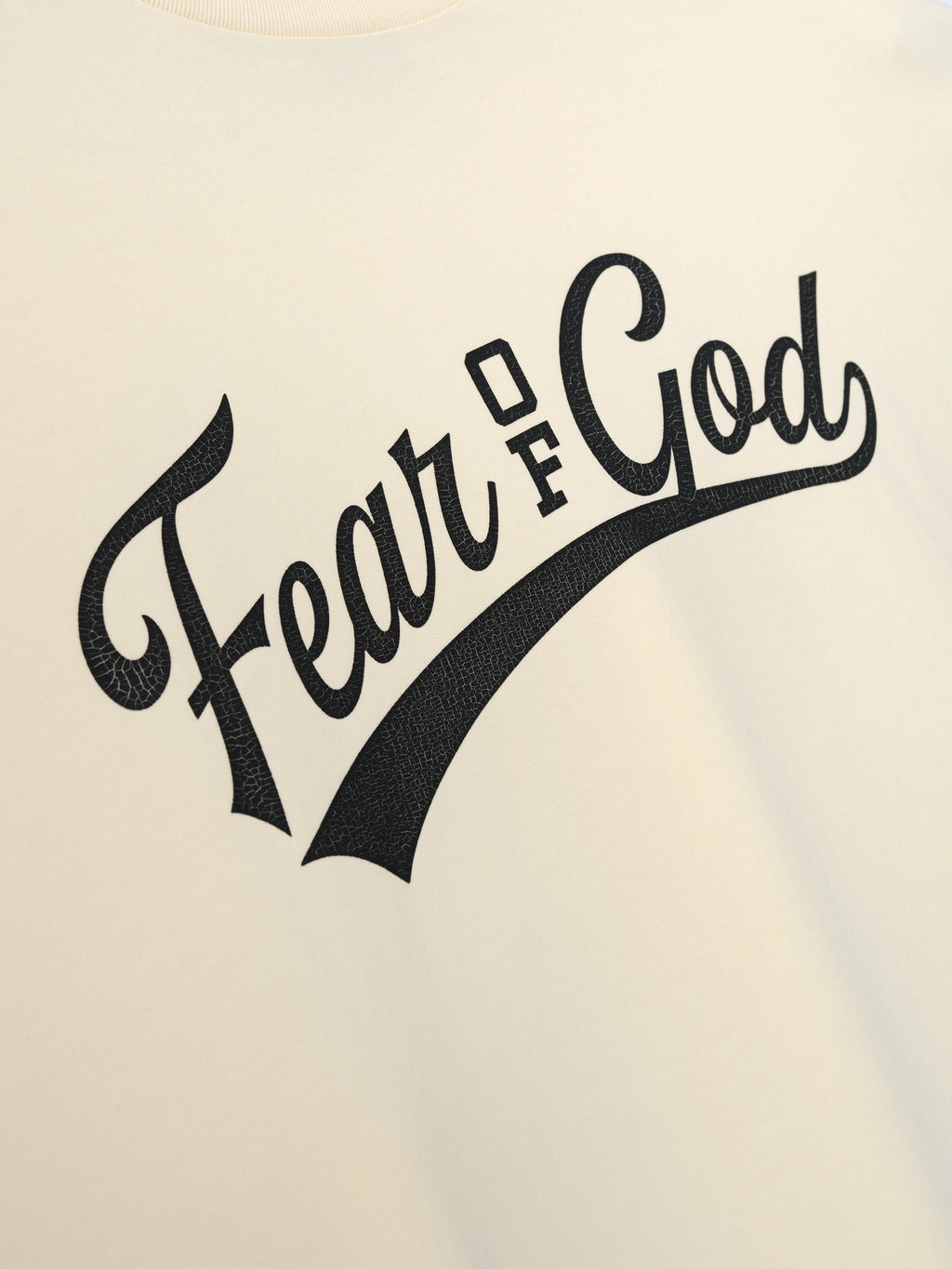 Merch Long Sleeve Tee in a soft off-white hue featuring a bold, textured black "Fear of God" script graphic across the chest for a sleek, modern look.