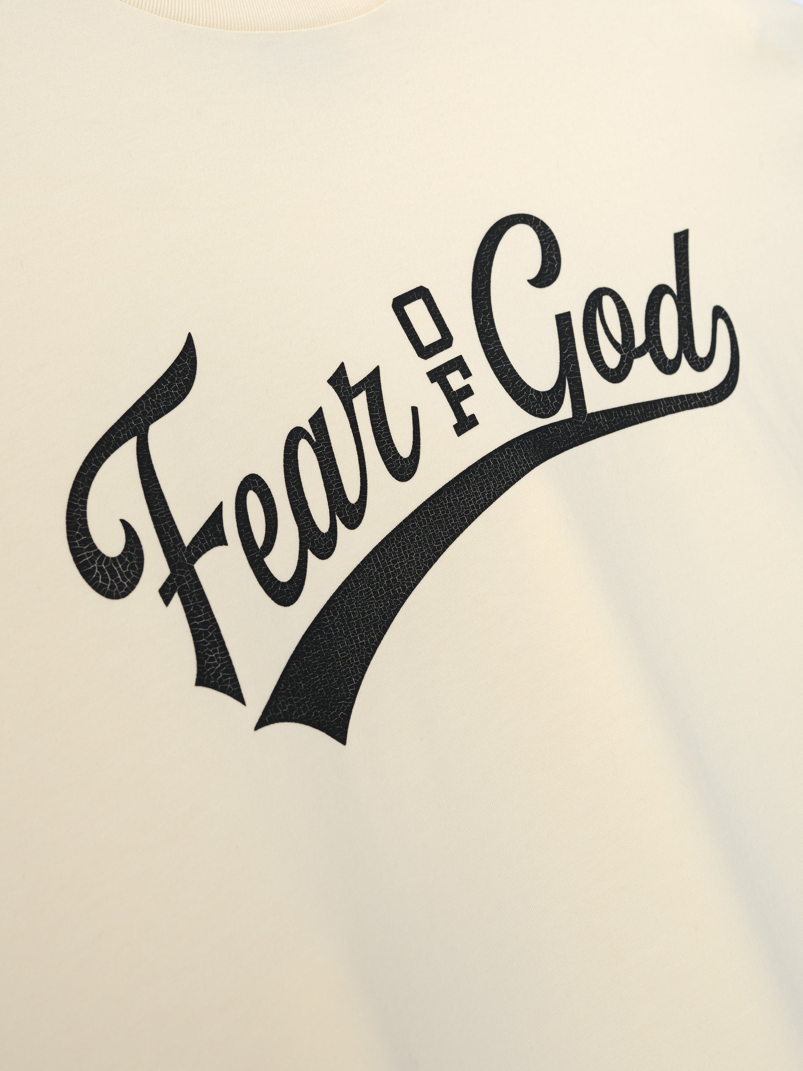 Merch Long Sleeve Tee in a soft off-white hue featuring a bold, textured black "Fear of God" script graphic across the chest for a sleek, modern look.