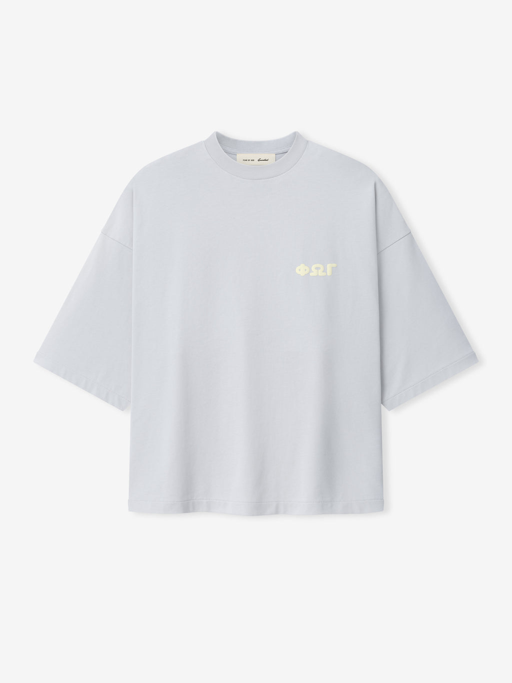 Merch Tee in a soft light grey shade with a relaxed, boxy fit and dropped shoulders, featuring small cream-colored Greek letter print on the chest for a minimalist look.