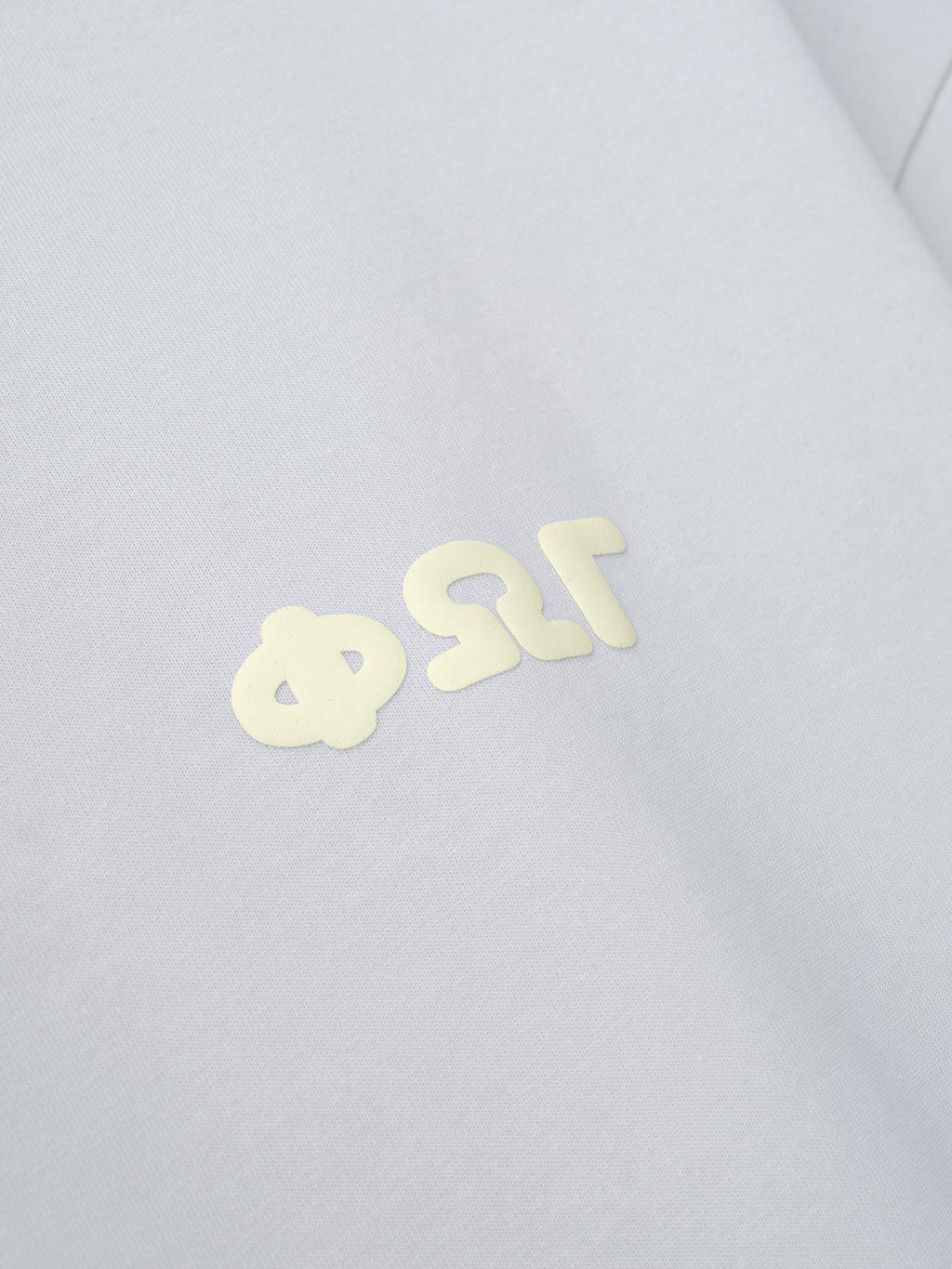 Merch Tee in a soft overcast shade with a subtle cream Greek letter design printed on the chest, offering a minimalist and clean aesthetic perfect for casual streetwear.