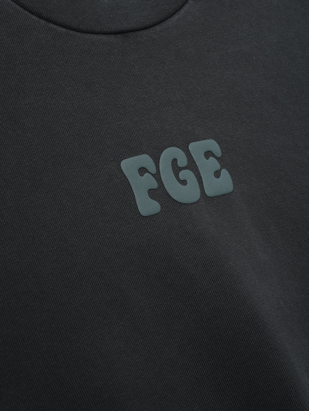 Heavy Jersey Merch Tee in a washed dark grey tone with a soft texture, featuring a small raised "FGE" logo on the chest for a sleek, minimalistic casual top.