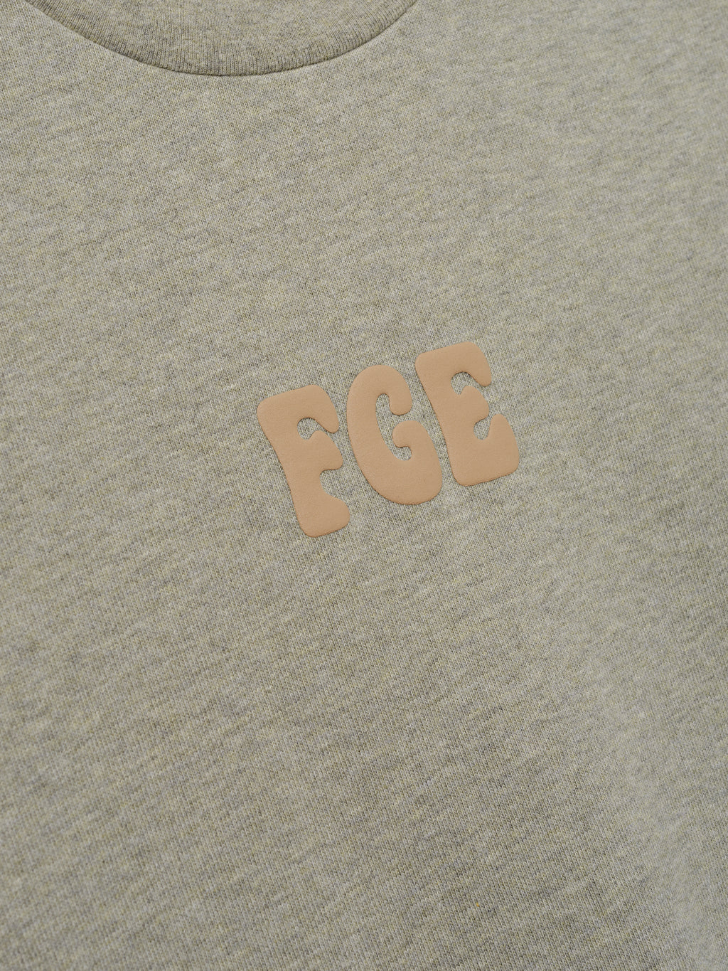 Heavy Jersey Merch Tee in a soft washed seal tone with a smooth texture, featuring small raised "FGE" lettering in a neutral beige on the chest for a subtle, refined casual top.