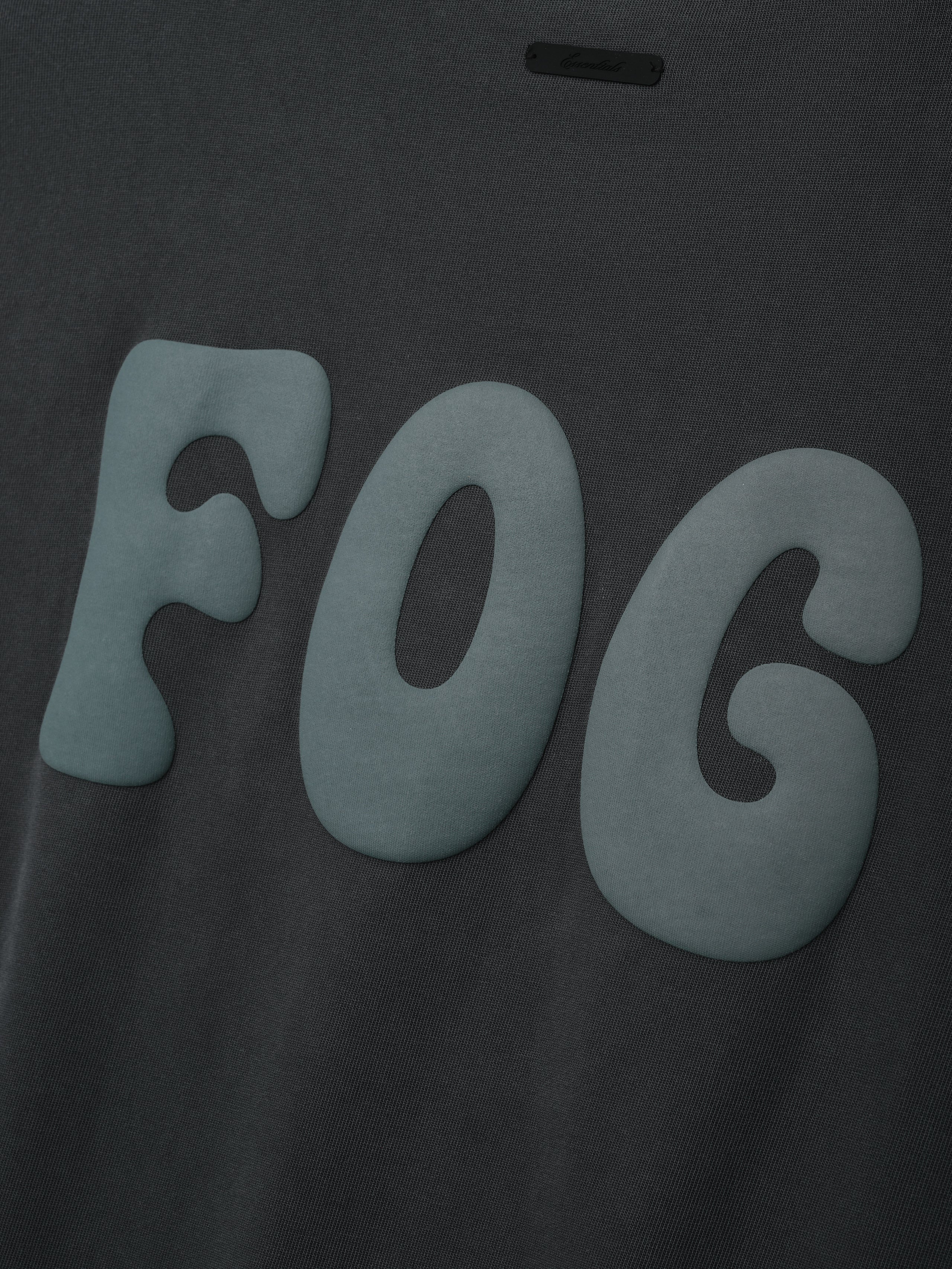 Heavy Jersey Merch Long Sleeve Tee in a dark washed grey fabric featuring large raised soft blue "FOG" lettering across the chest for a bold, modern streetwear top.
