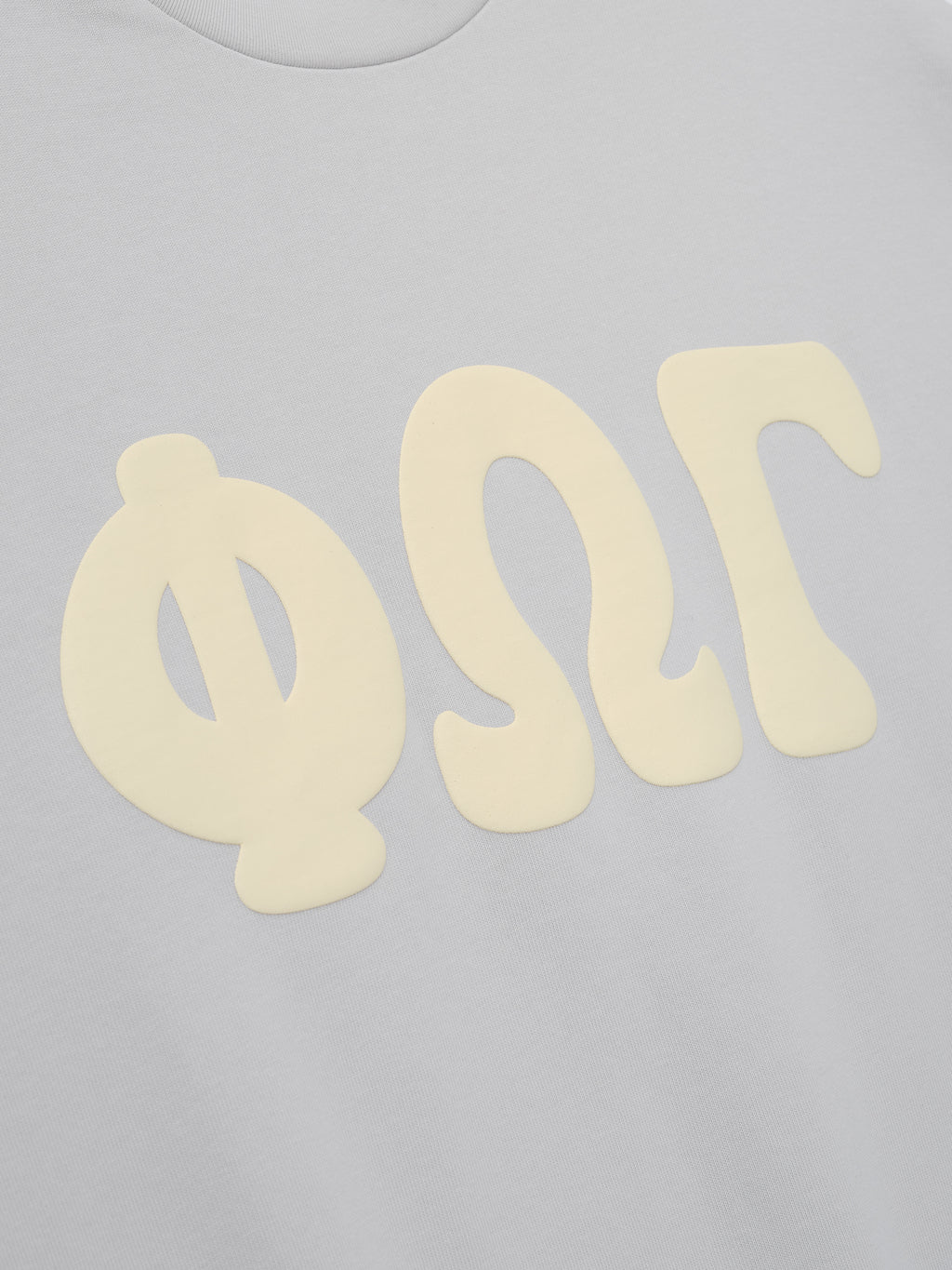Heavy Jersey Merch Long Sleeve Tee in a soft overcast grey tone featuring large cream Greek letter graphics printed on the chest for a casual, modern top.