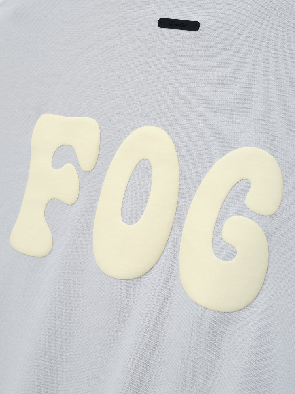 Heavy Jersey Merch Long Sleeve Tee in a soft overcast grey featuring large cream "FOG" graphic letters printed with a raised, textured effect for a bold streetwear statement.