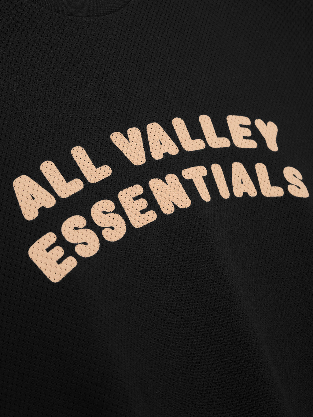 Sport Mesh Merch Long Sleeve Tee in vintage black featuring breathable mesh fabric with curved soft beige "ALL VALLEY ESSENTIALS" lettering on the chest for a casual sporty top.